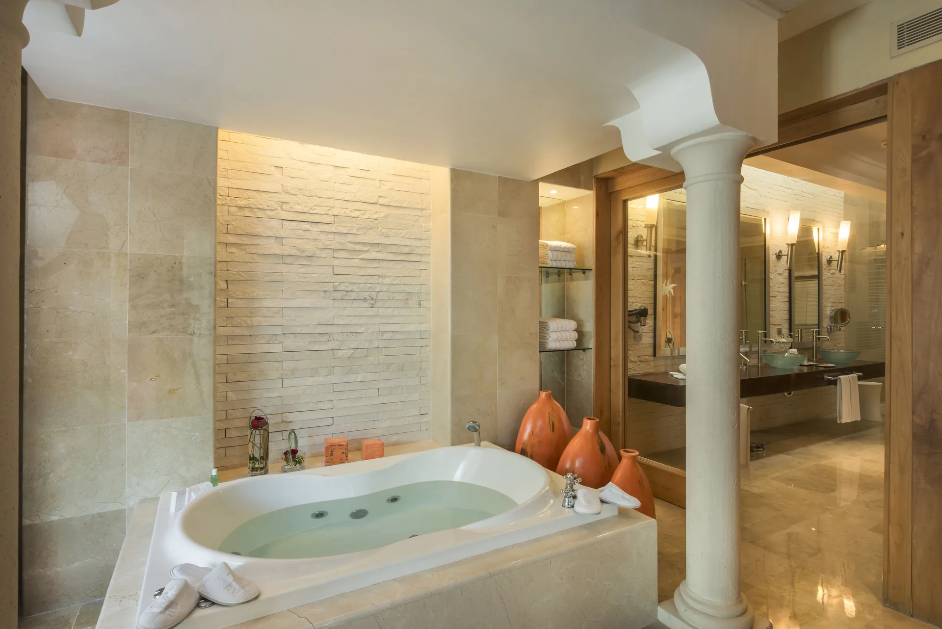 Romantic Villa bathroom tub with stone walls and vanity beyond at JOIA Paraíso by Iberostar.