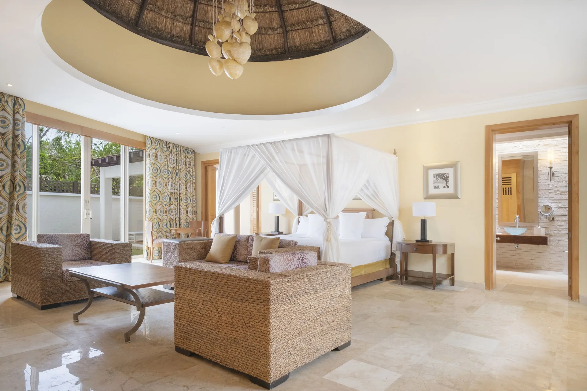Spacious Romantic Villa at JOIA Paraíso by Iberostar with canopy bed, seating area, and bathroom entrance.