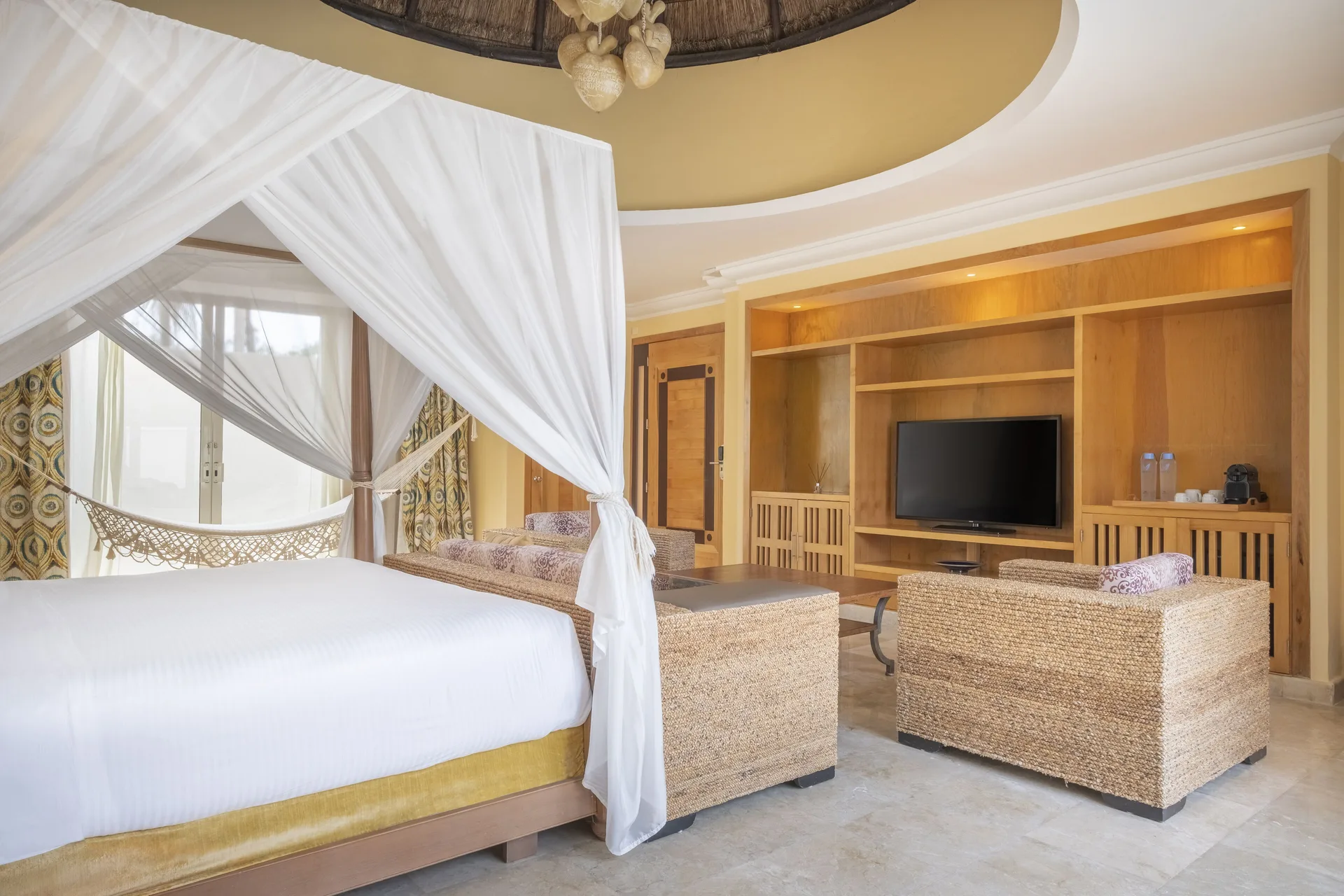 Romantic Villa at JOIA Paraíso by Iberostar with canopy bed, lounge seating, and TV wall.