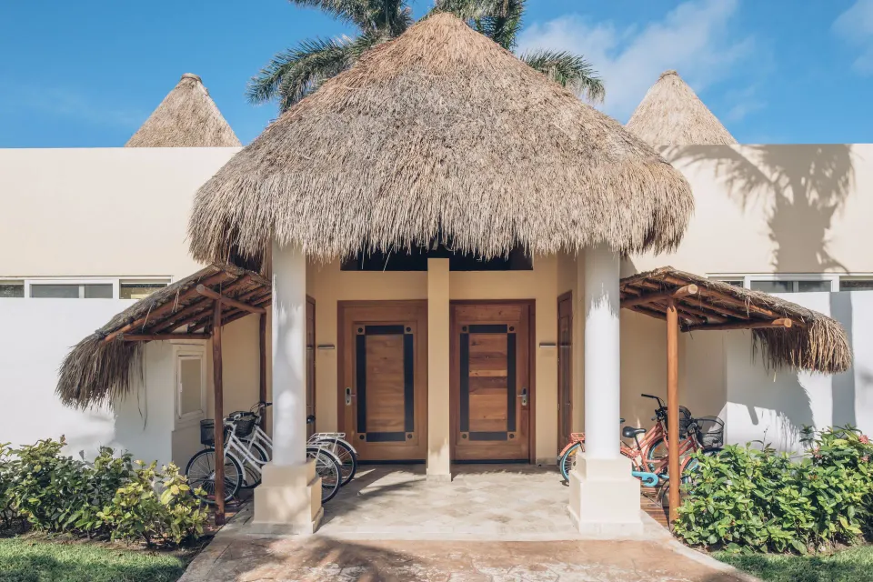 Thatched entrance to a Romantic Villa at JOIA Paraíso by Iberostar with bicycles parked outside.