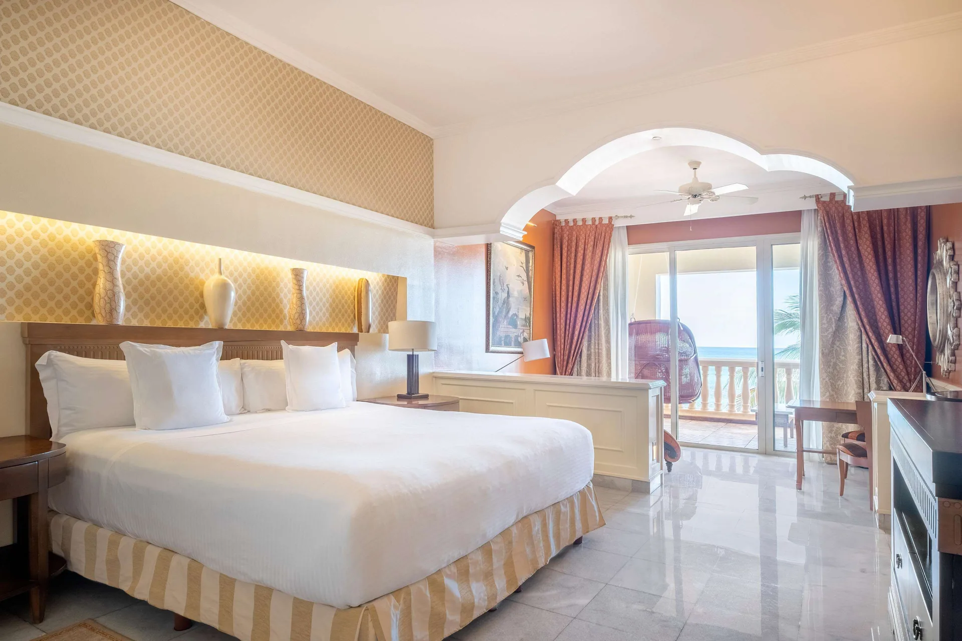 Oceanfront Suite bedroom with king bed, balcony doors and sea beyond at JOIA Paraíso by Iberostar.