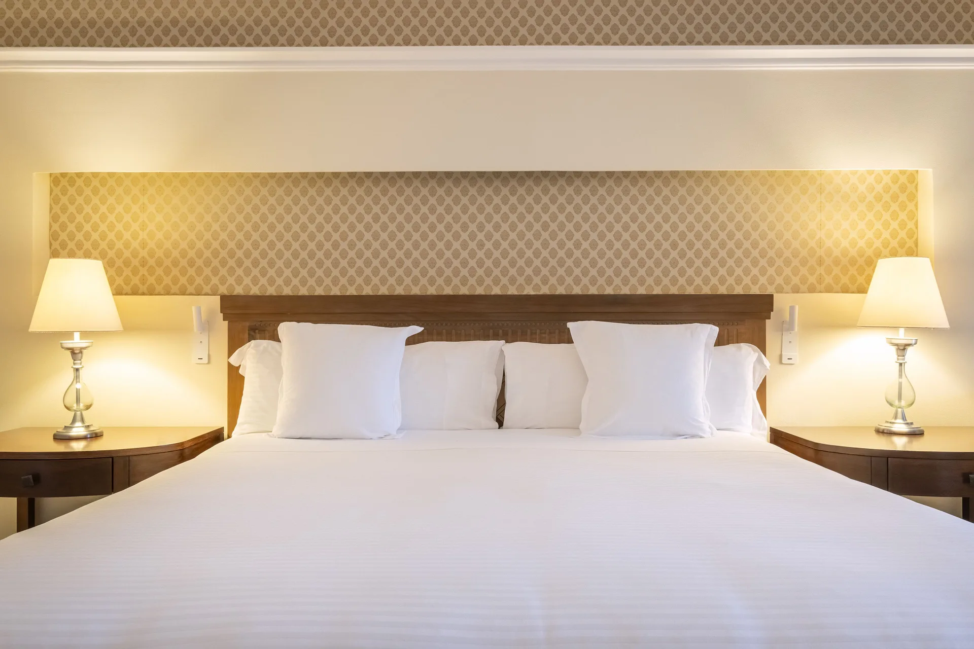 Oceanfront Suite king bed with white linens and lamps at JOIA Paraíso by Iberostar.