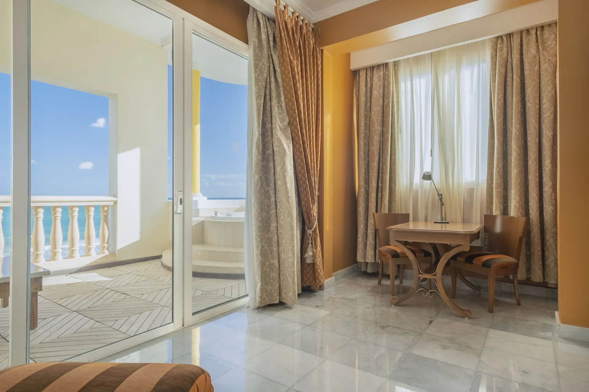 Oceanfront suite seating and balcony doors at JOIA Paraíso by Iberostar.