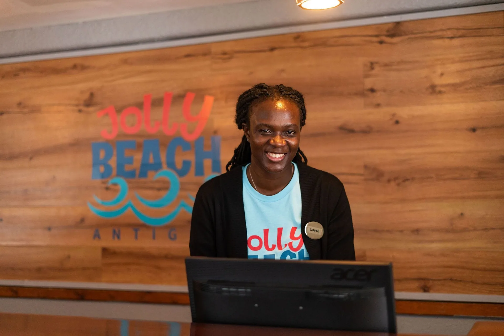 Smiling front desk staff member behind the reception counter at Jolly Beach Antigua.