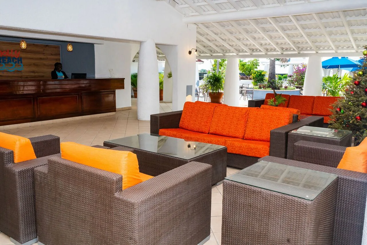 Lobby seating area with orange cushions and reception desk at Jolly Beach Antigua.