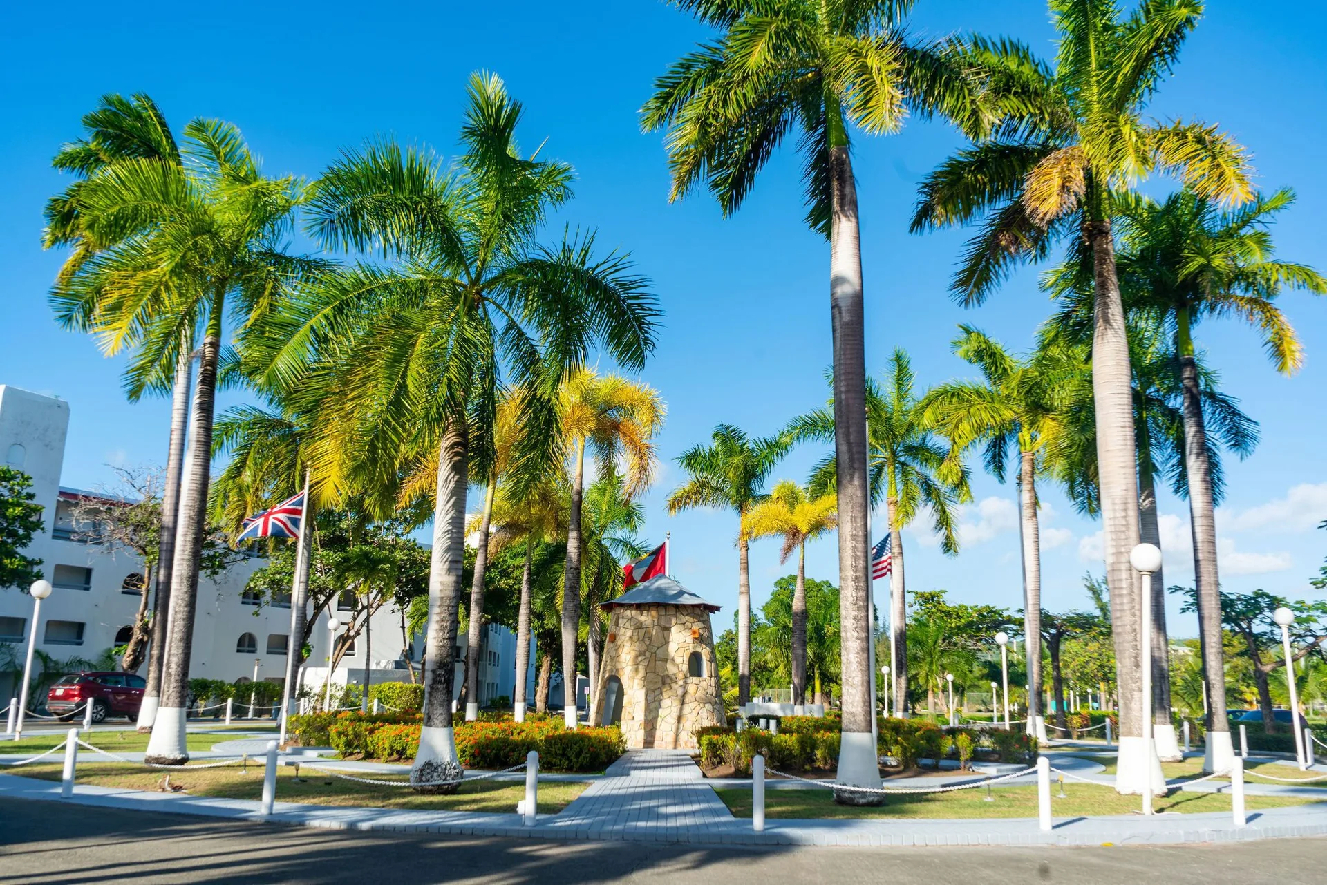 Palm-lined entrance drive with flags and a stone feature at Jolly Beach Antigua.