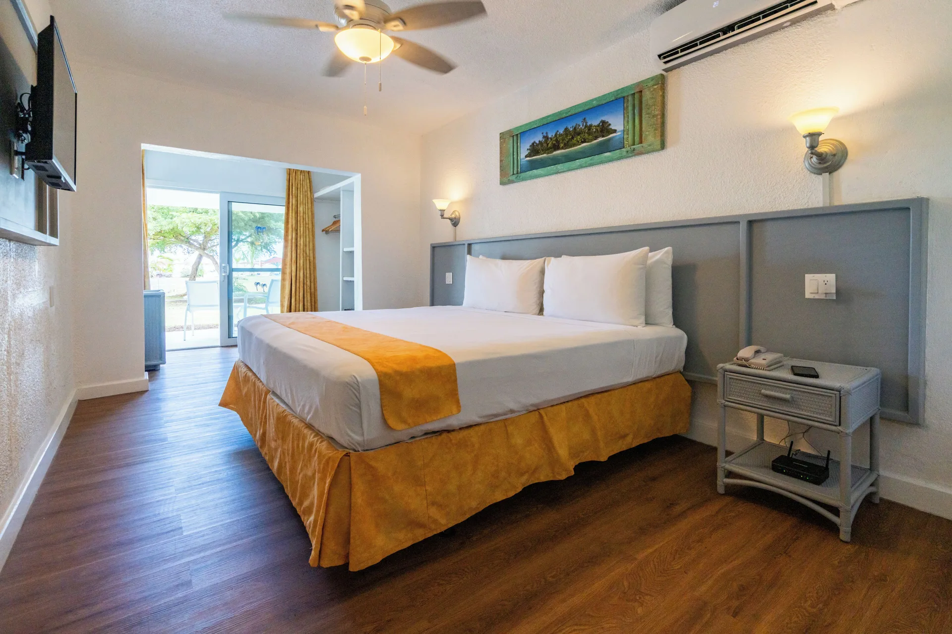 Superior Room king bed with balcony doors and wall-mounted TV at Jolly Beach Antigua.