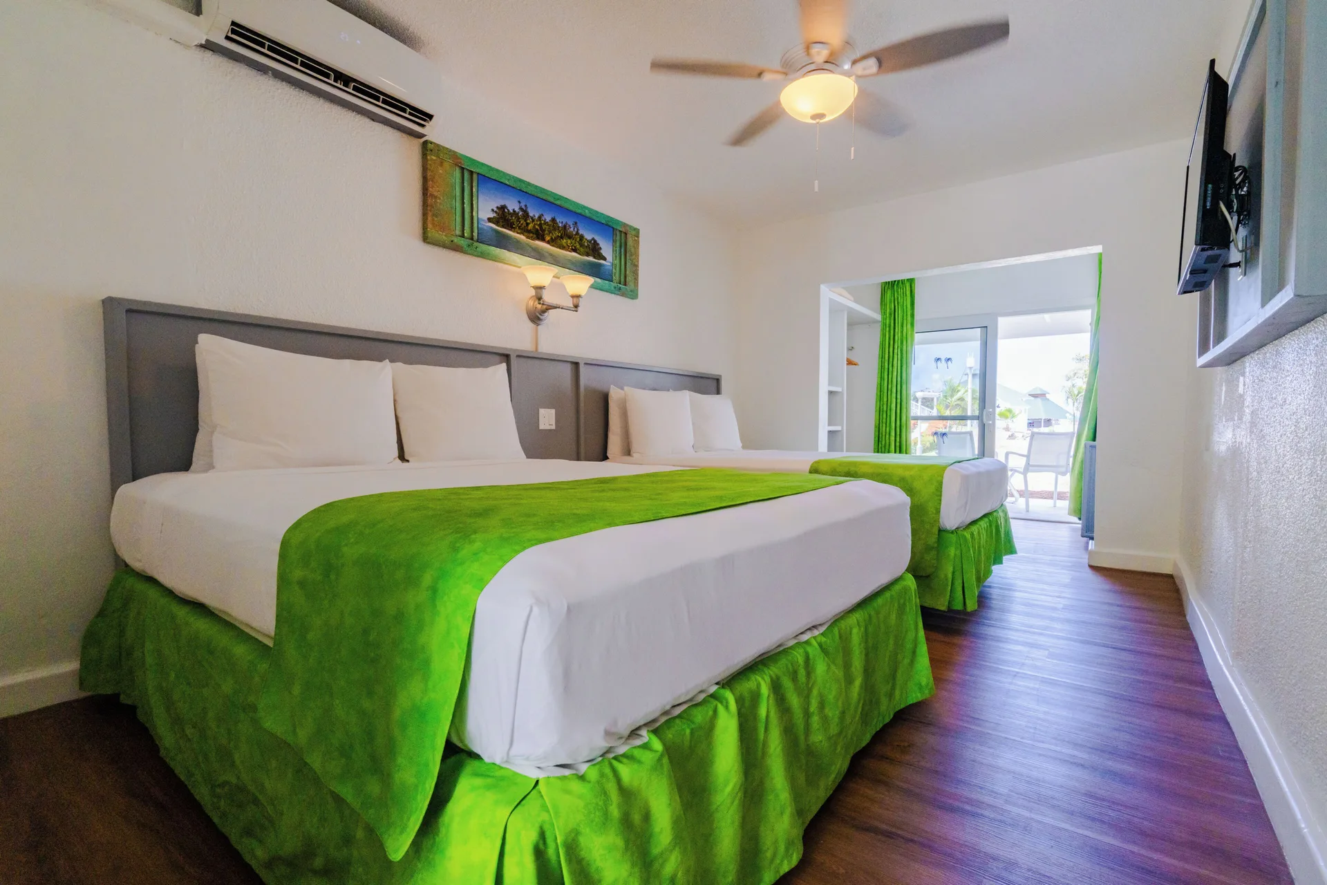 Superior room with two beds, green accents and balcony beyond at Jolly Beach Antigua.
