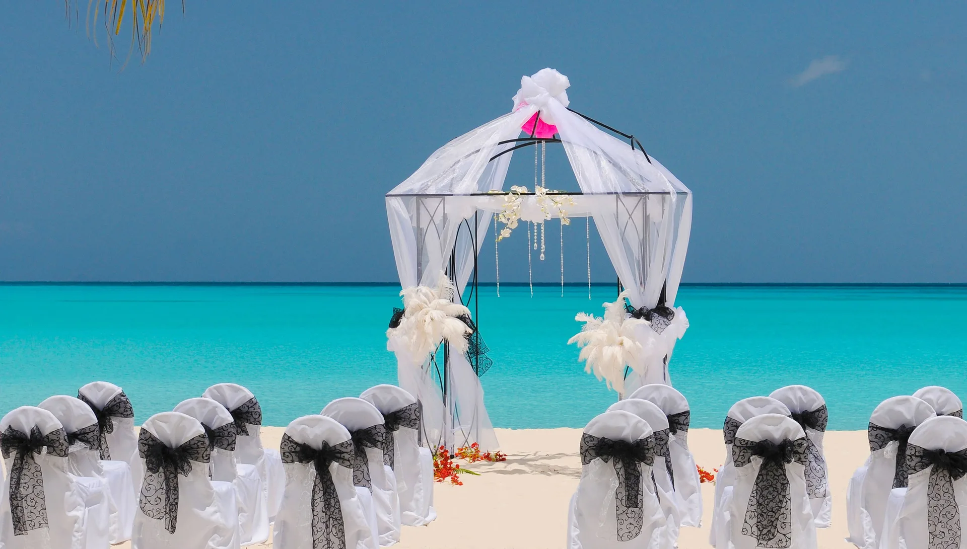 Beach wedding setup with white chairs and an arch at Jolly Beach Antigua.
