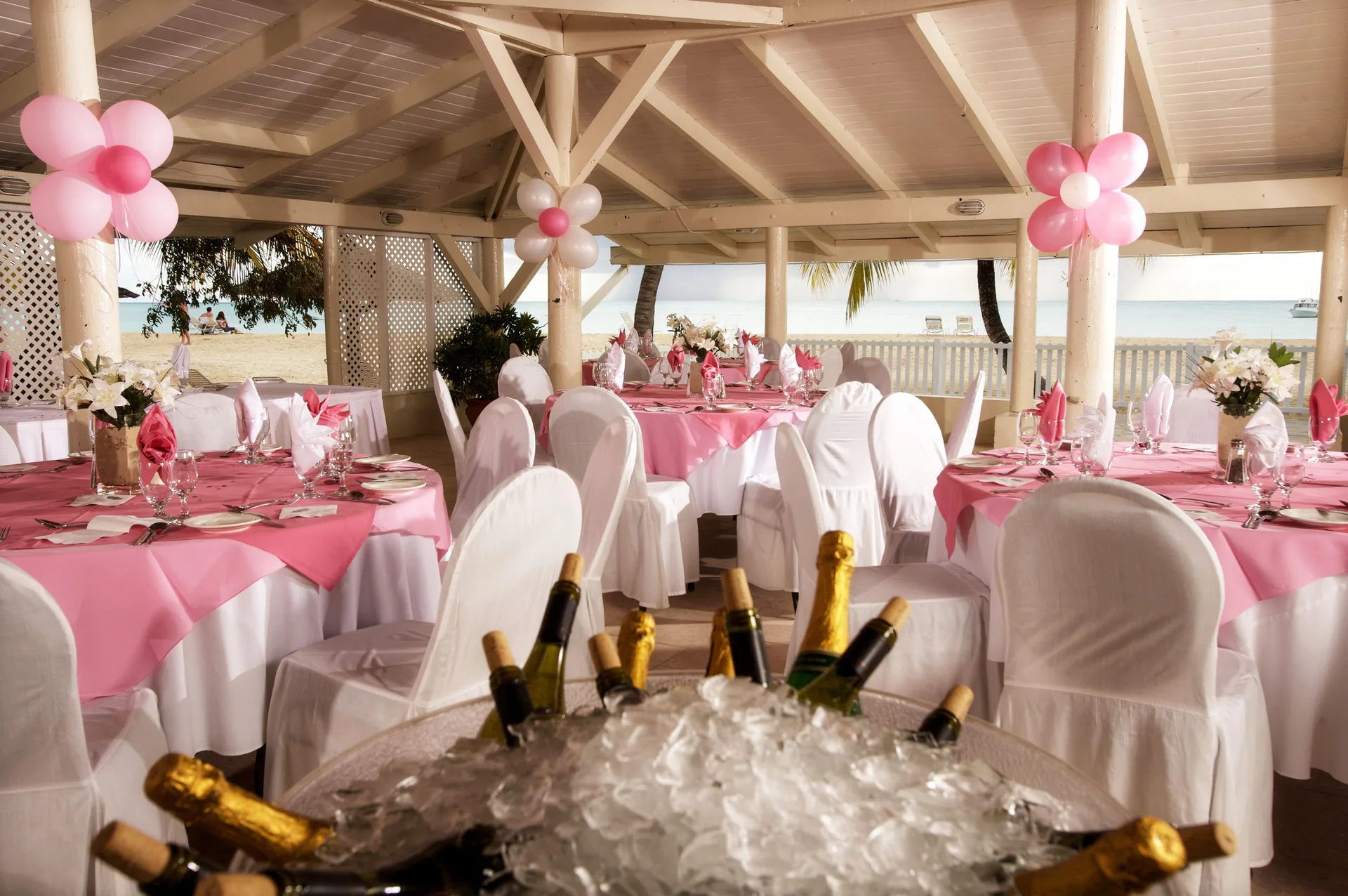 Pink-and-white event tables in a beachfront pavilion at Jolly Beach Antigua.