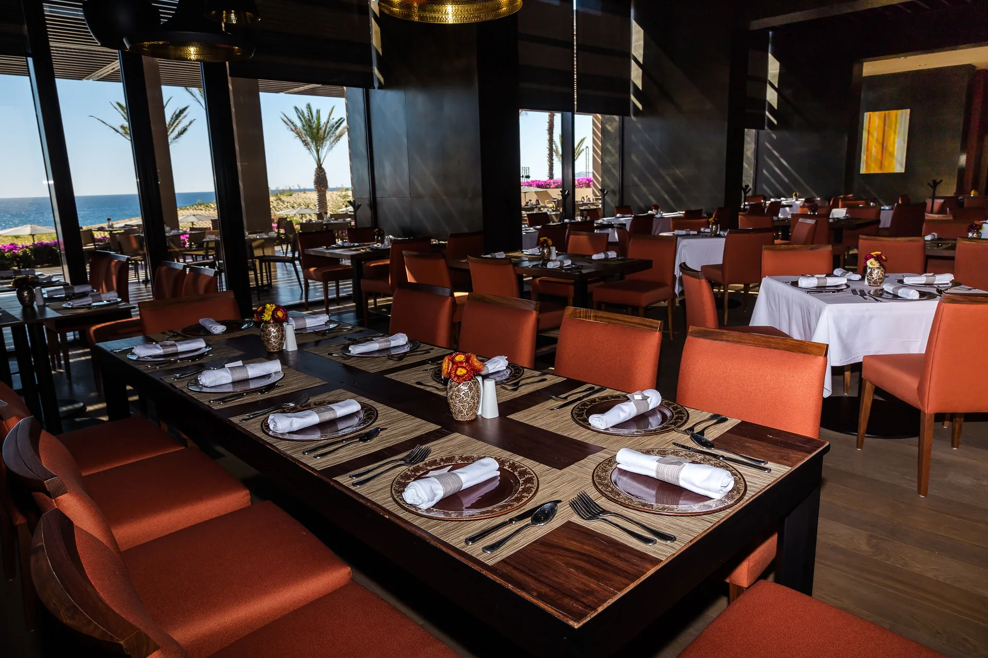 Restaurant dining room with ocean views and orange chairs at JW Marriott Los Cabos Beach Resort & Spa.