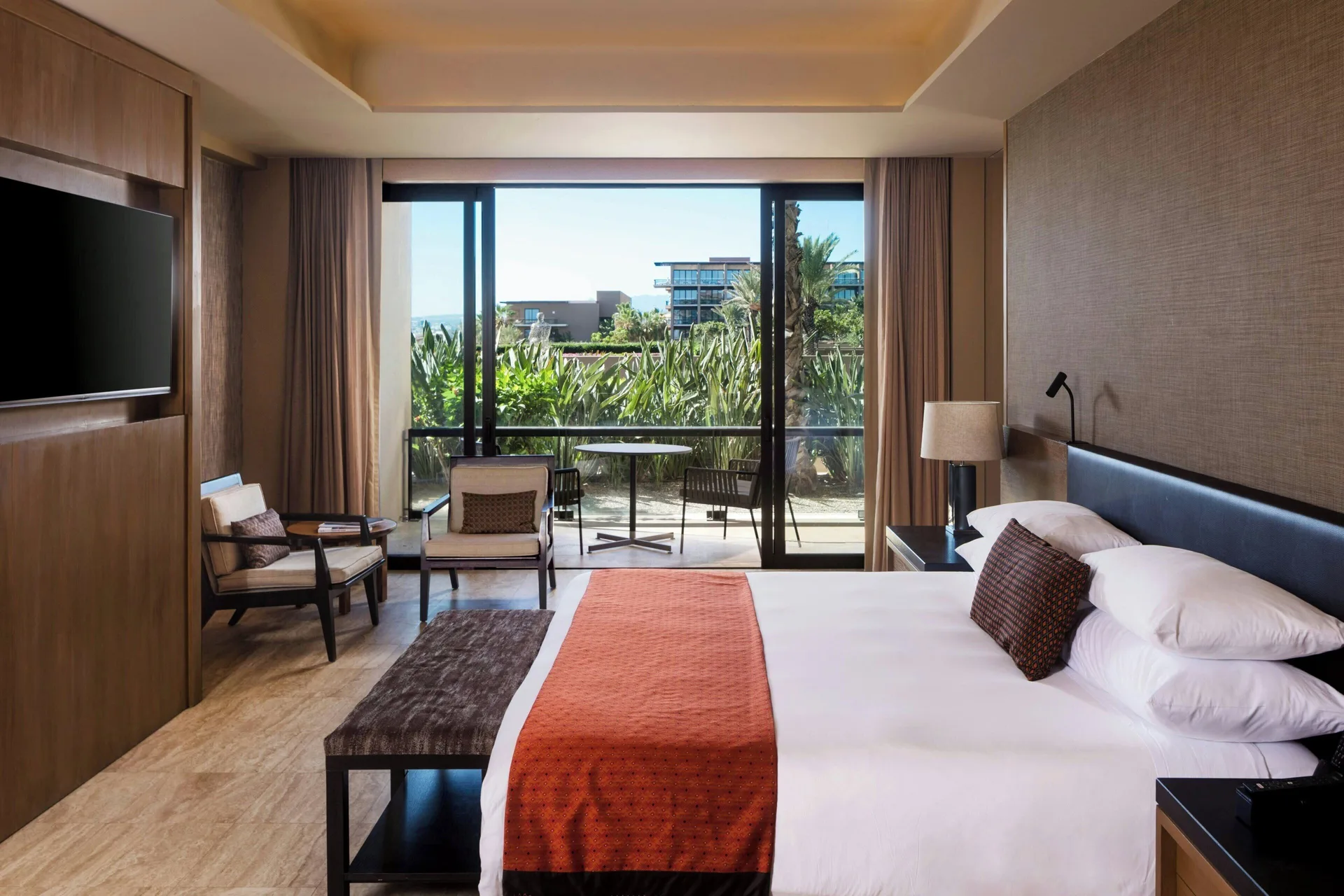Luxury Suite bedroom with king bed and resort-view balcony at JW Marriott Los Cabos Beach Resort & Spa.