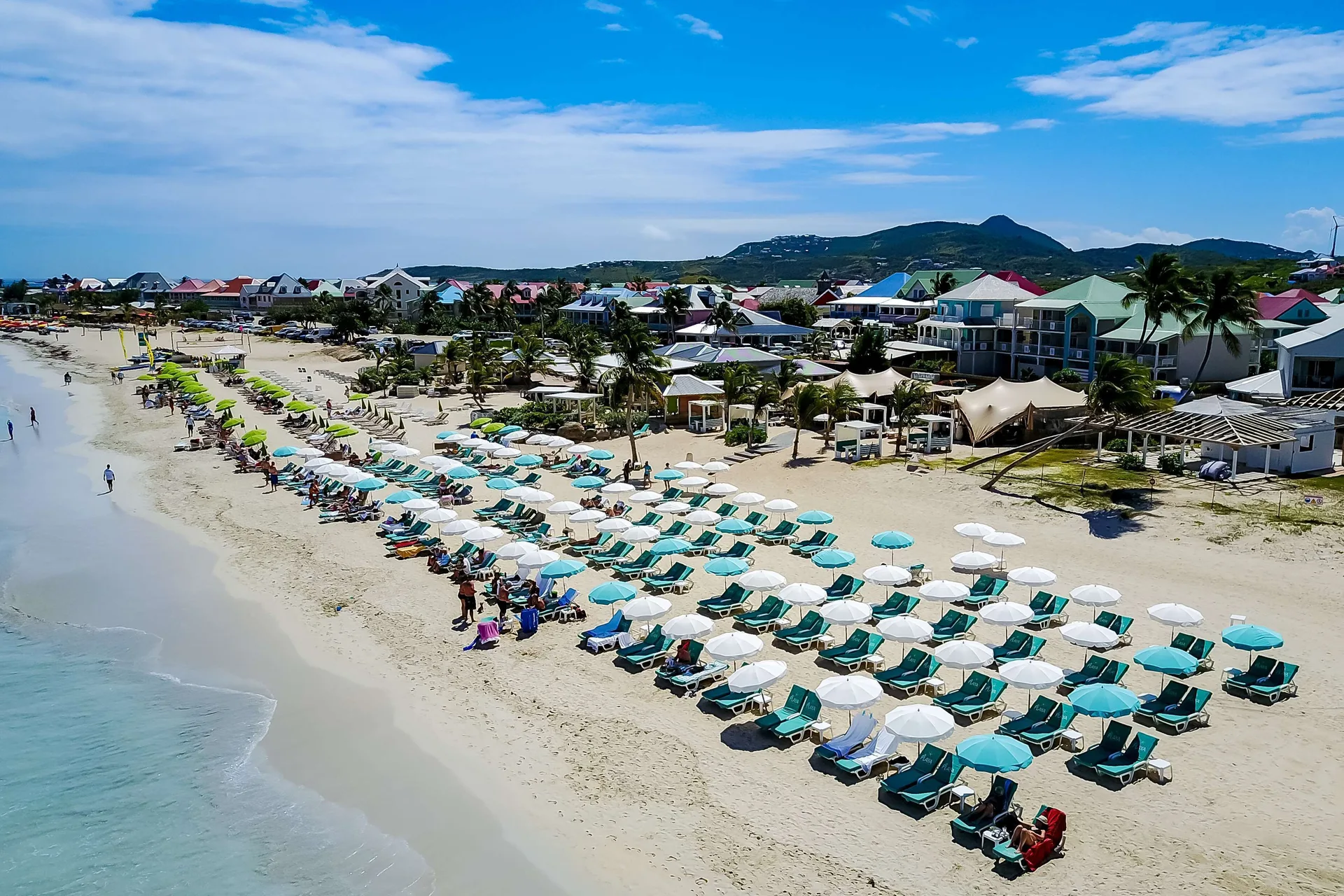 Aerial view of beach loungers and umbrellas along the shore at La Playa Orient Bay.