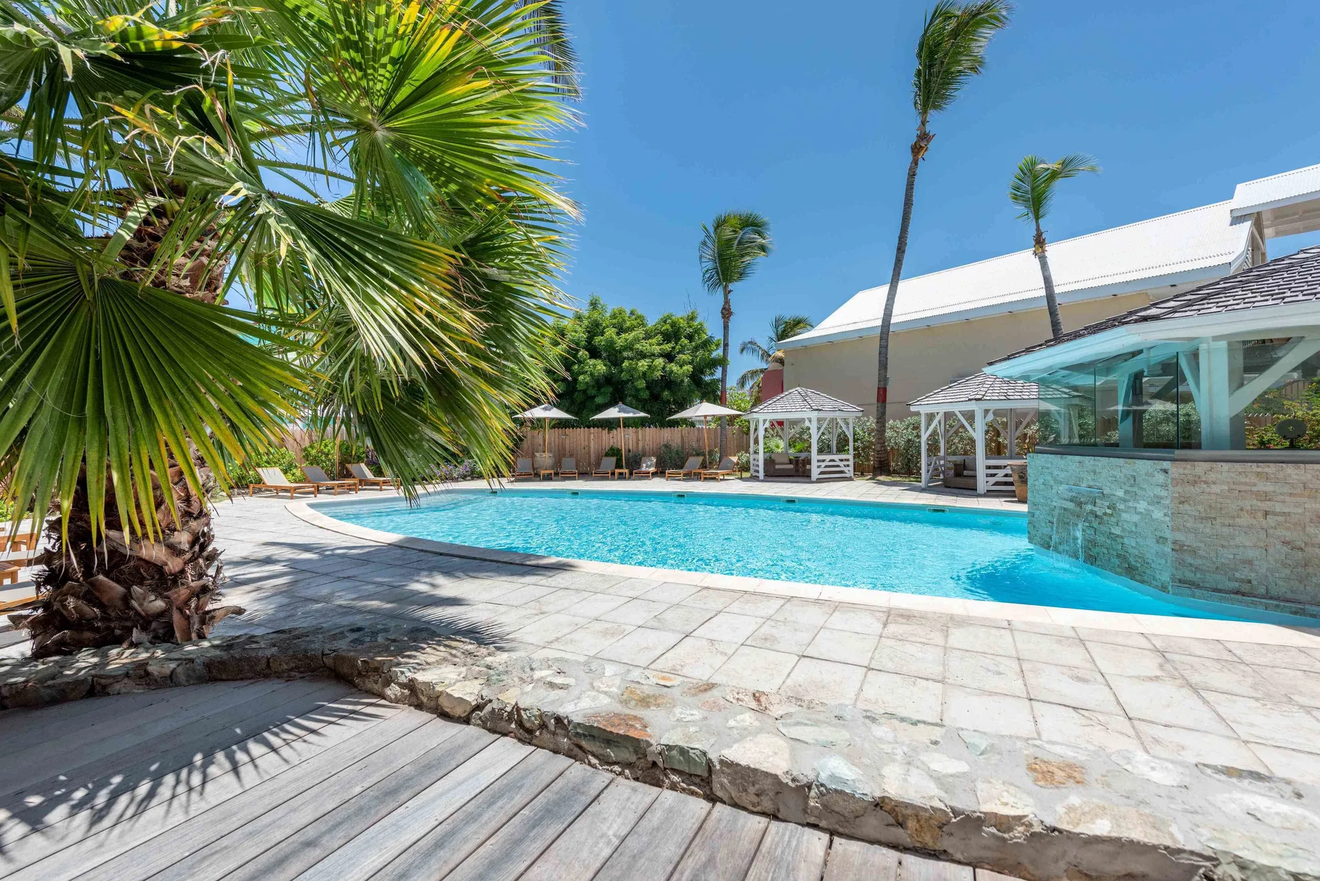 Pool beside a palm tree, cabanas and a stone water feature at La Playa Orient Bay.