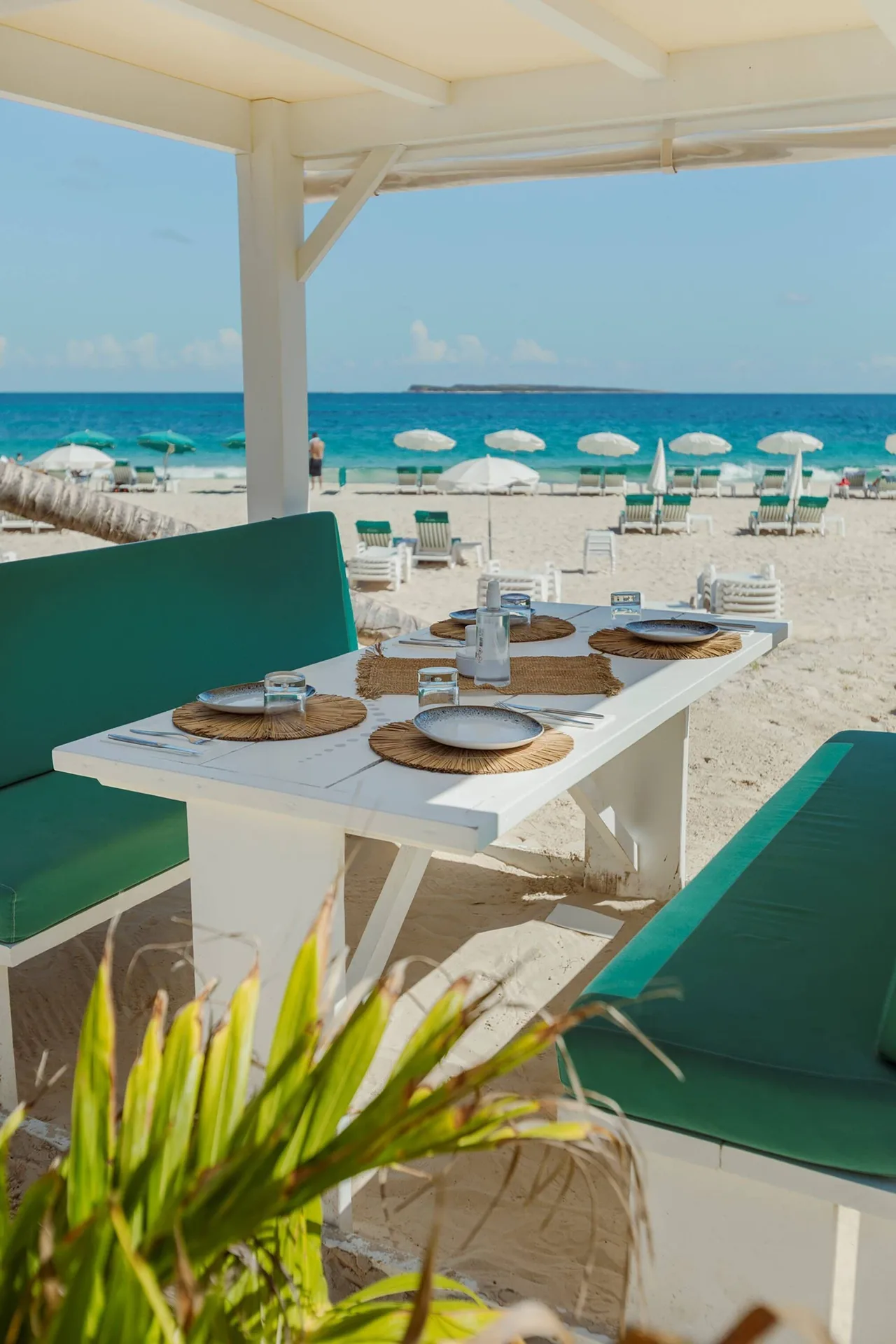Beachfront dining table with turquoise benches and ocean view at La Playa Orient Bay.