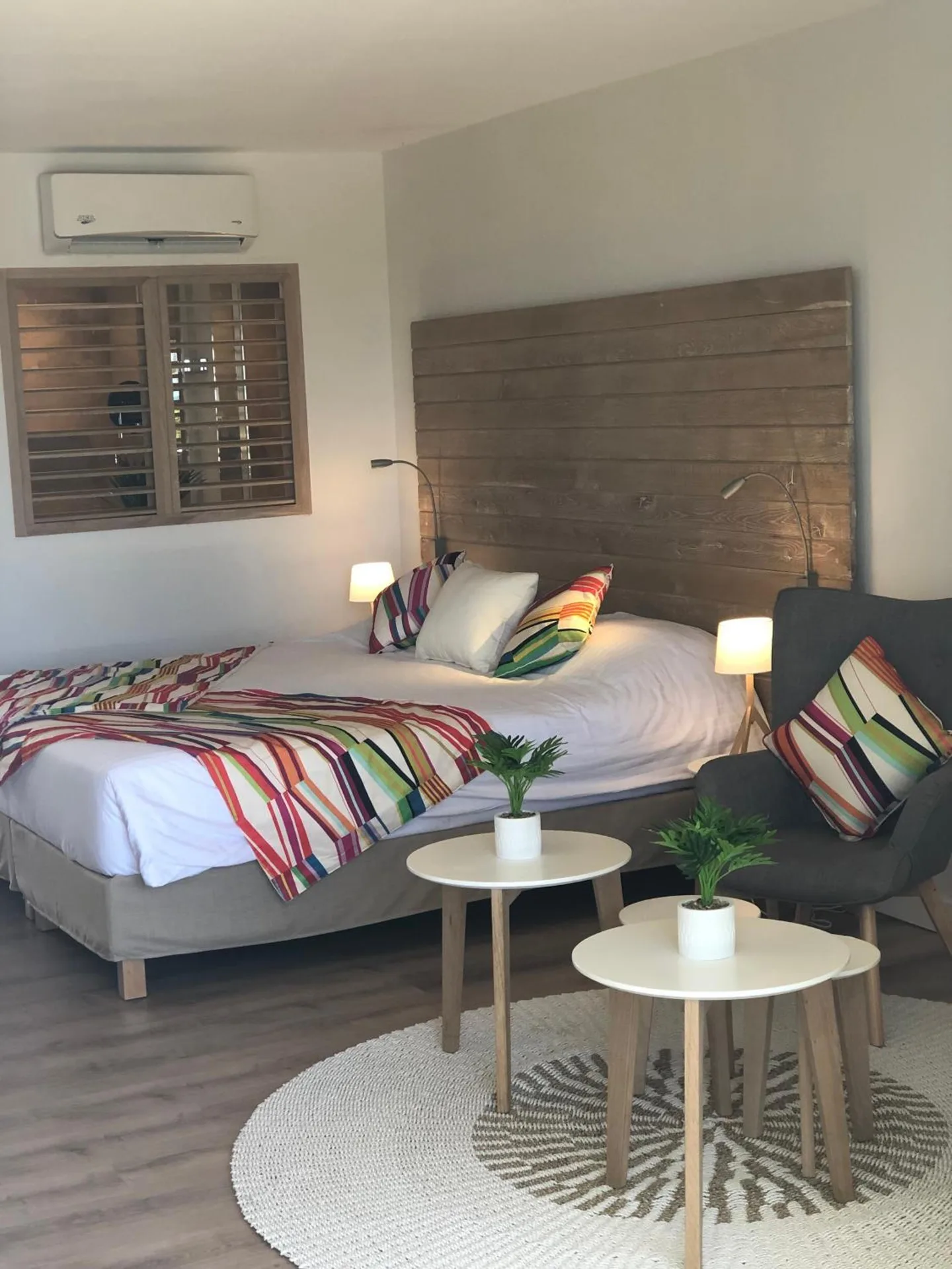 Classic Junior Suite bed and seating area at La Playa Orient Bay with colorful pillows and wood headboard.