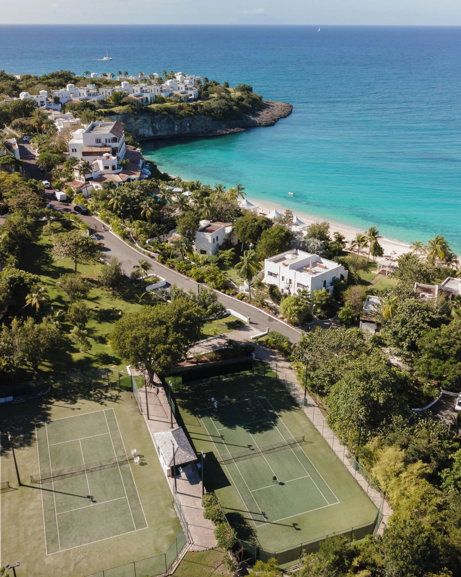 Aerial view of tennis courts, resort buildings, beach, and sea at La Samanna, St Martin.