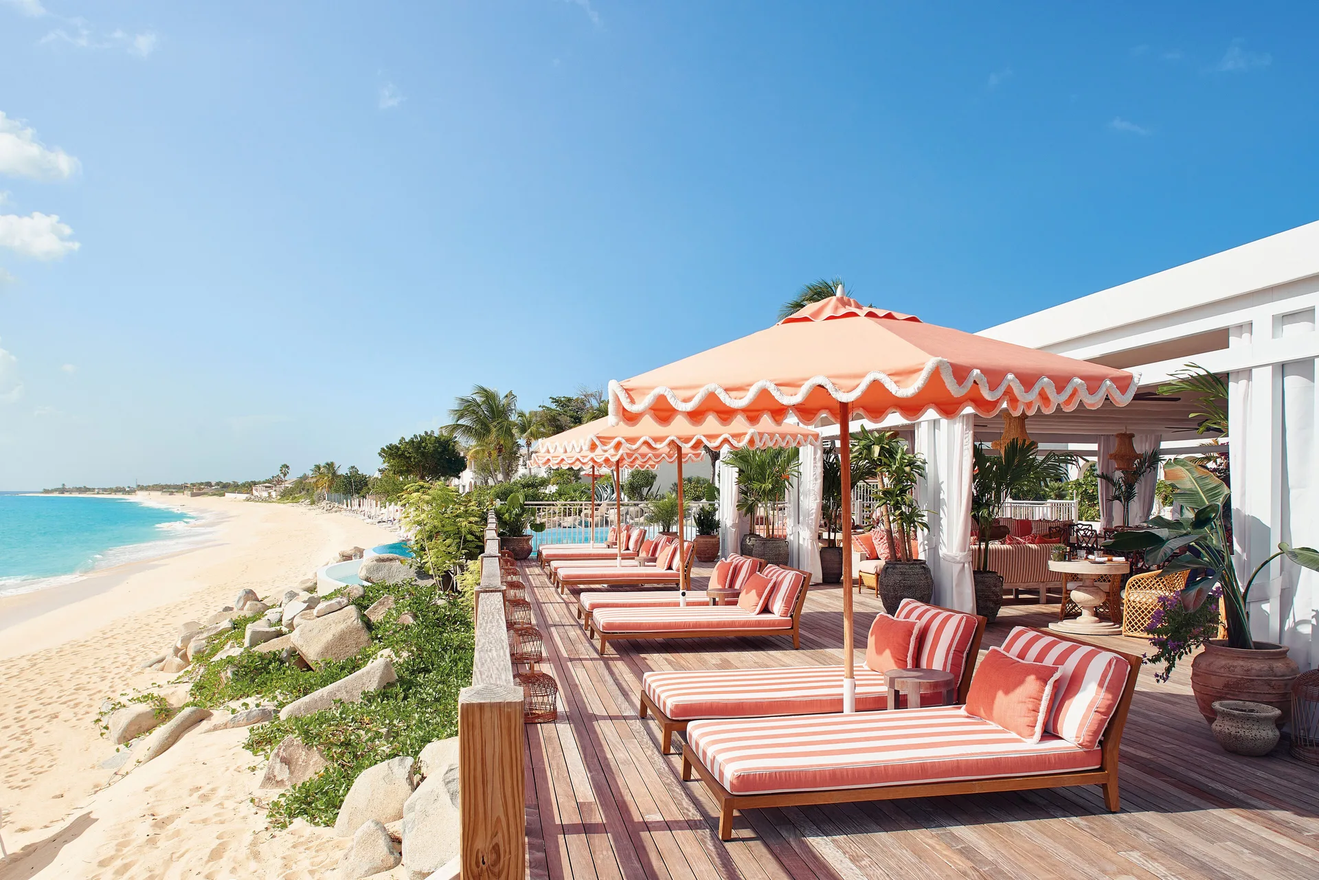 Beachfront deck with striped loungers and orange umbrellas at La Samanna, St Martin.