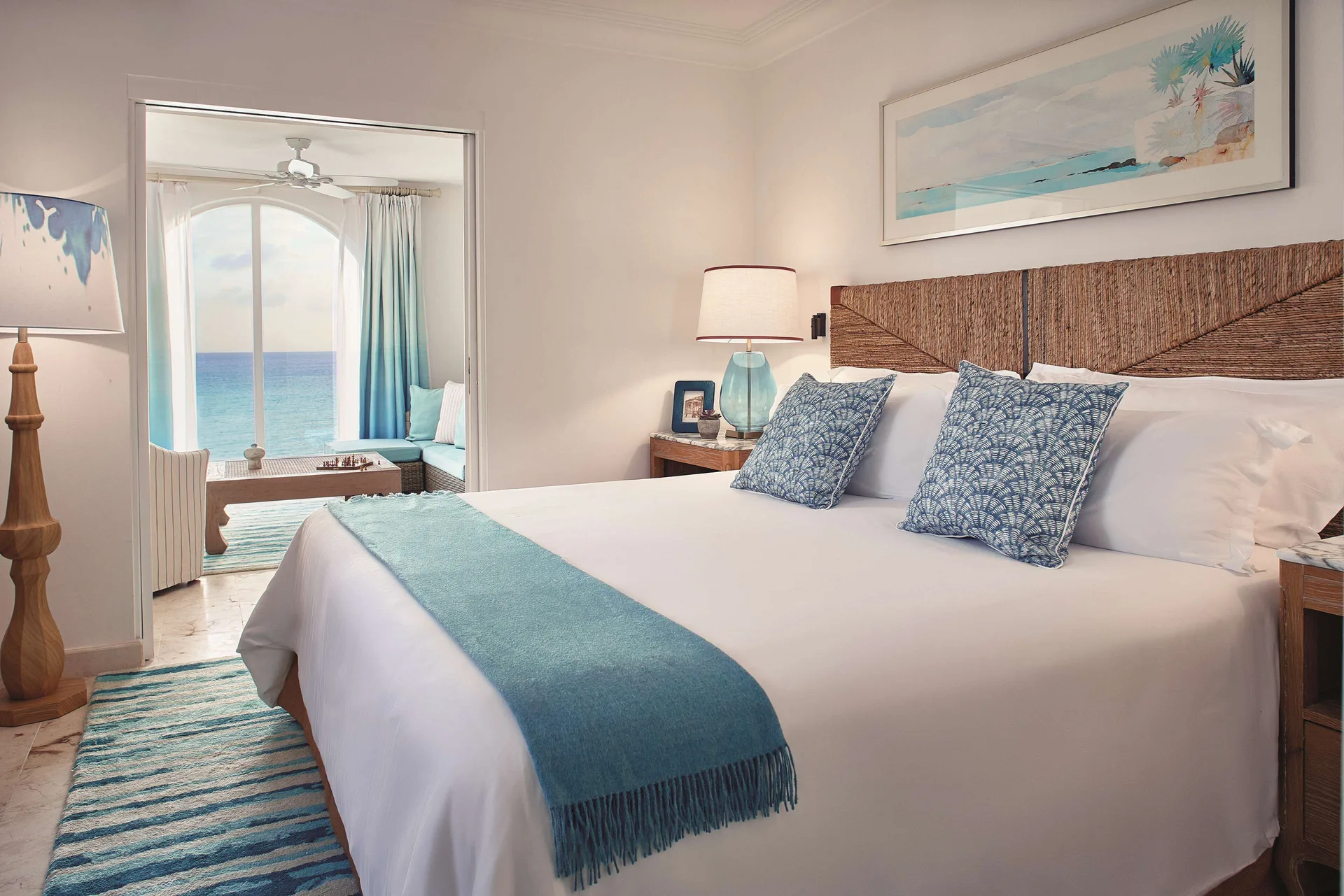 King bed in a one-bedroom terrace suite at La Samanna, St Martin, with the sea visible beyond.