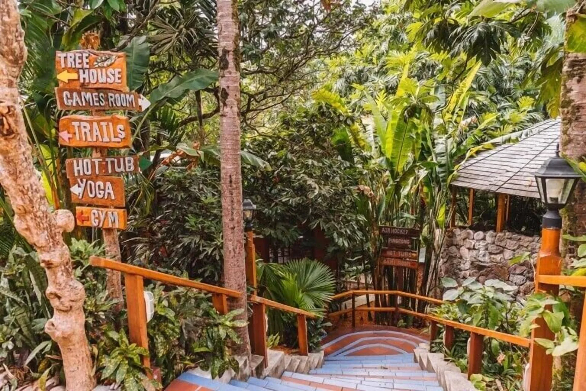Wooden stairway with directional signs through tropical gardens at Ladera Resort.