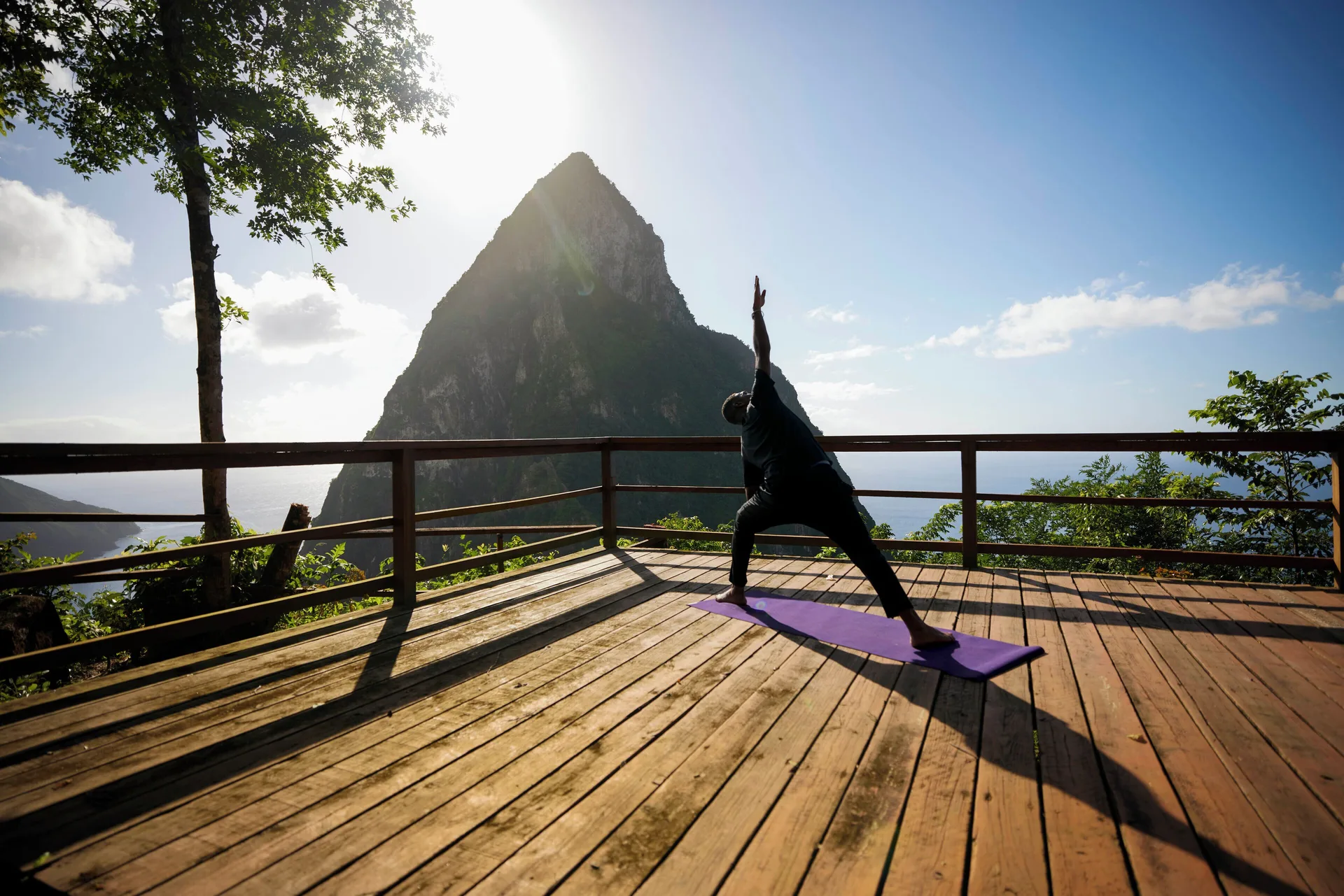 A guest practices yoga on a wooden deck with a Piton view at Ladera Resort.
