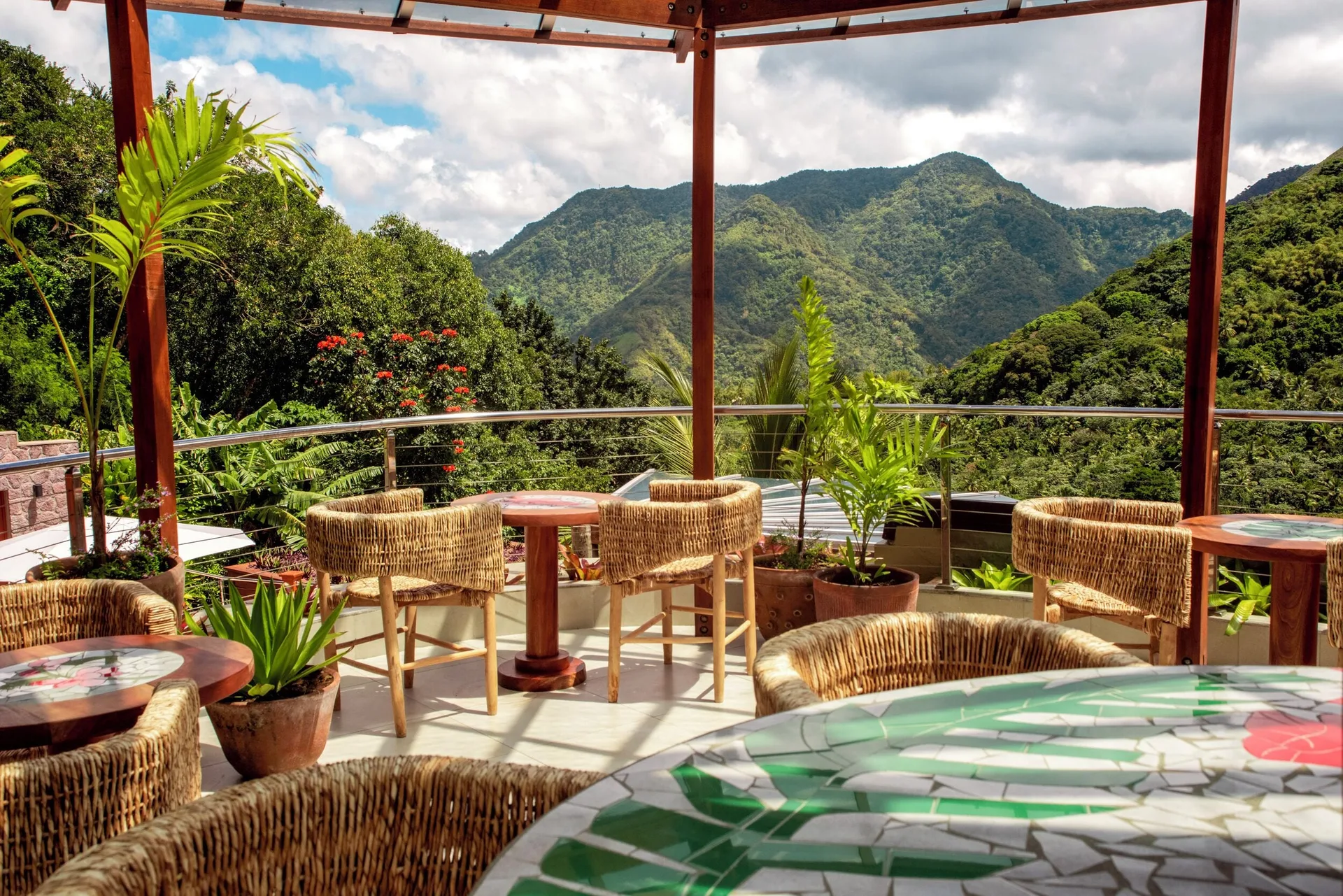 A terrace with wicker chairs, mosaic tables, and mountain views at Ladera Resort.