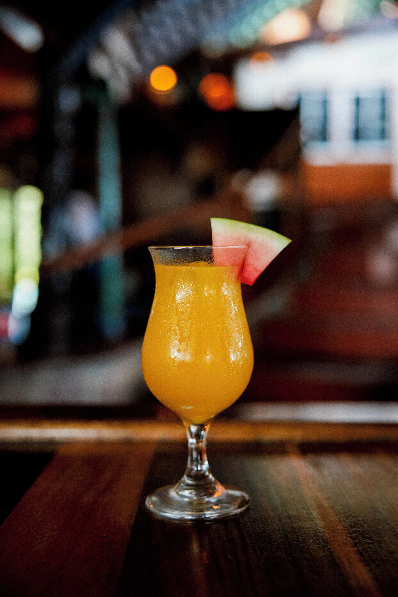 A yellow cocktail with a watermelon garnish sits on a bar at Ladera Resort.