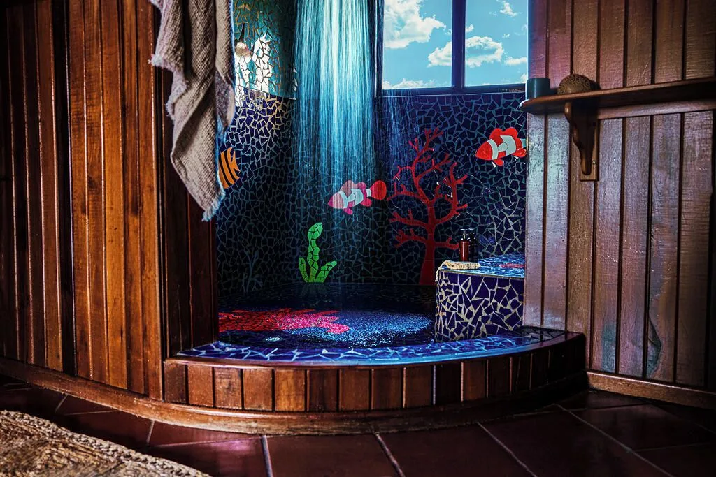 Mosaic-tiled shower at Ladera Resort with colorful fish and coral designs in a wooden bathroom.