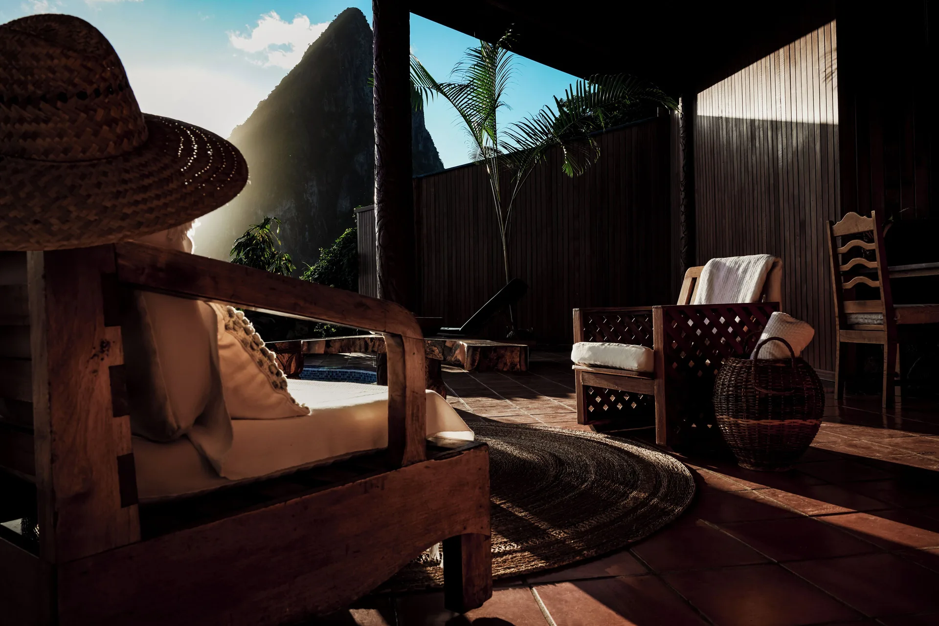 Shaded suite terrace at Ladera Resort with wooden chairs, woven basket, and a Piton view.