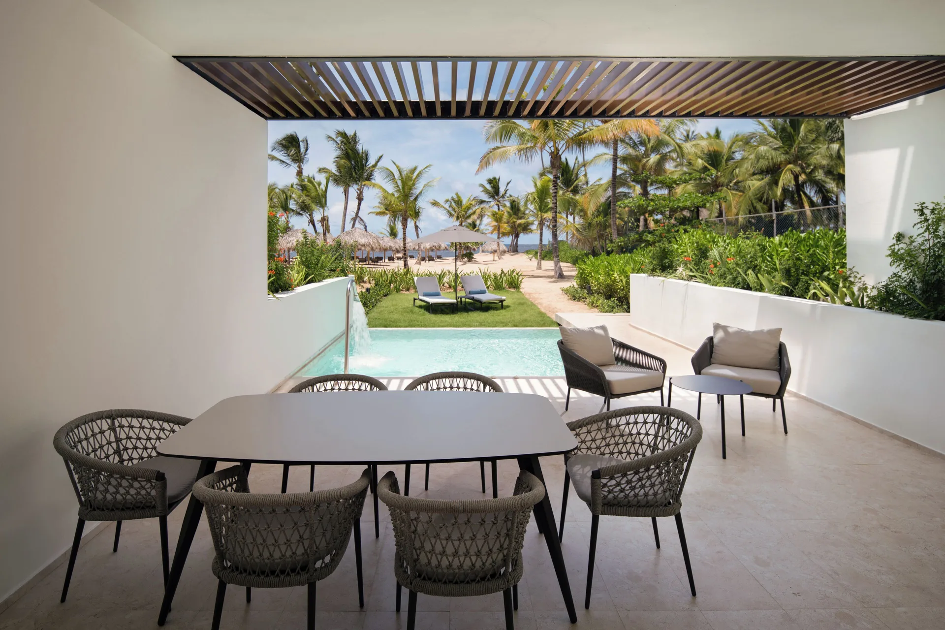 Covered terrace with dining table, plunge pool, and beach view at Live Aqua Punta Cana.