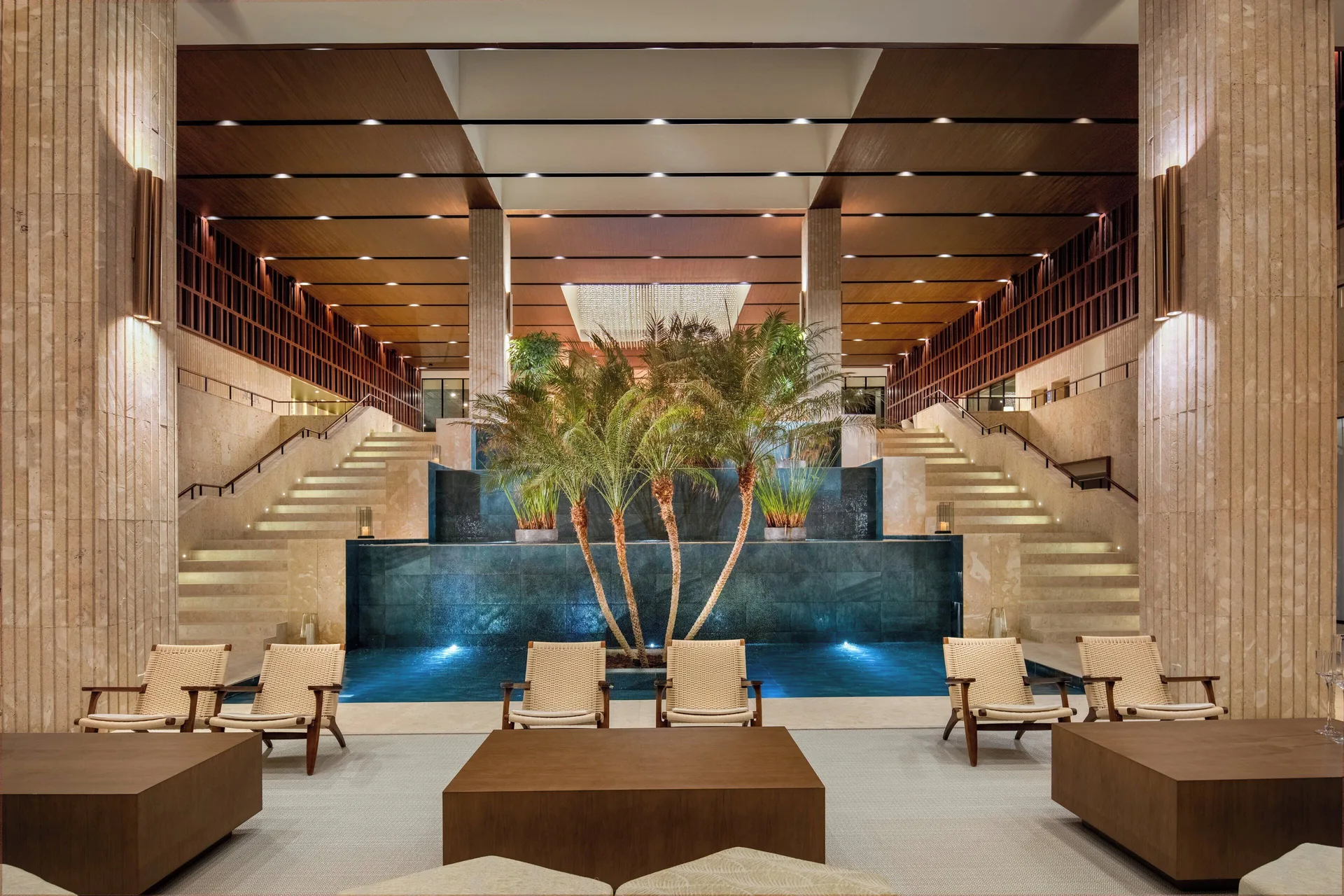 Lobby water feature with palms, staircases, and lounge chairs at Live Aqua Punta Cana.