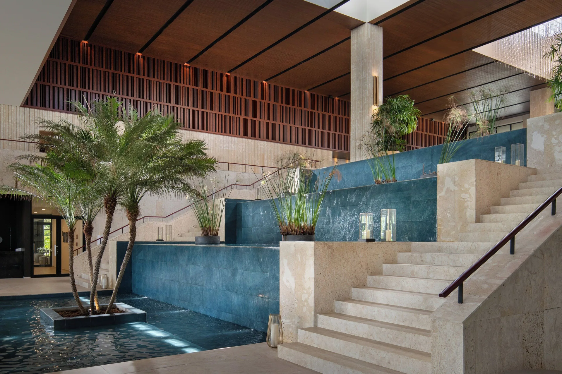 Blue-tiled lobby water feature beside stairs at Live Aqua Punta Cana.