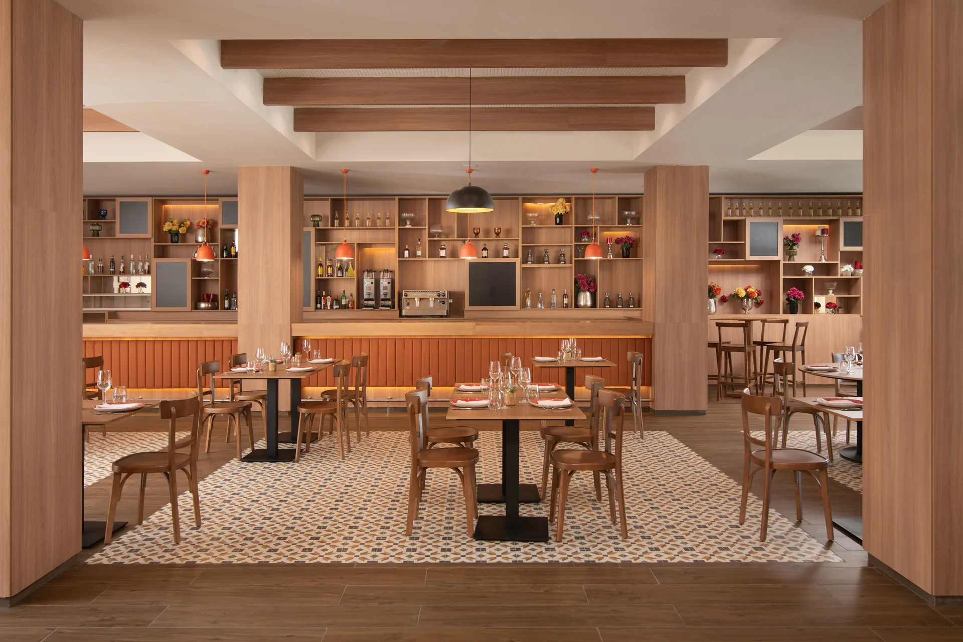Restaurant dining room with set tables, wood shelving, and a bar at Live Aqua Punta Cana.