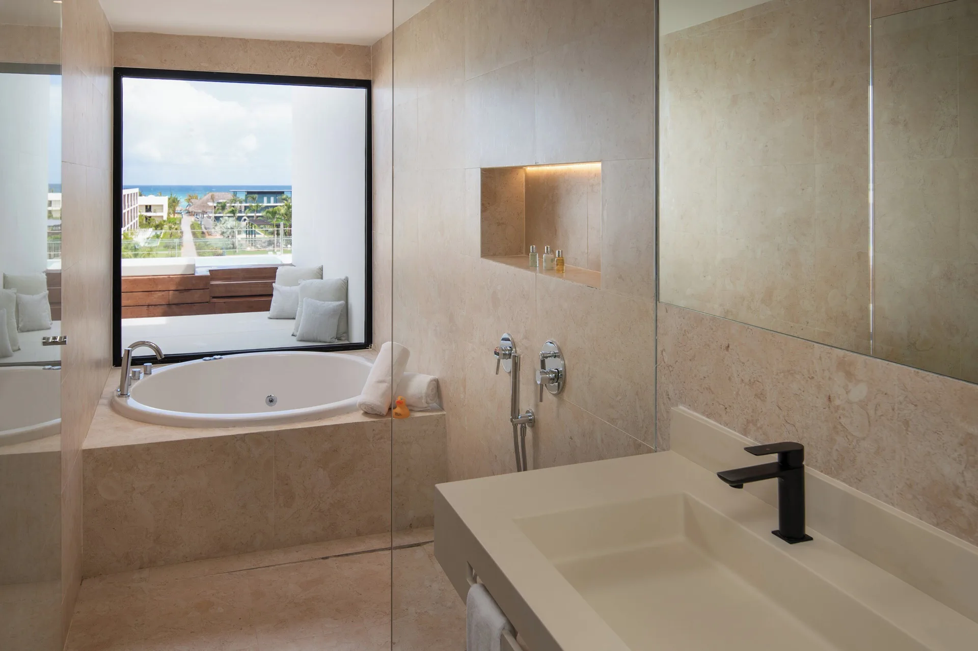 Fuego Suite Partial Ocean View bathroom with tub, sink and window at Live Aqua Punta Cana.