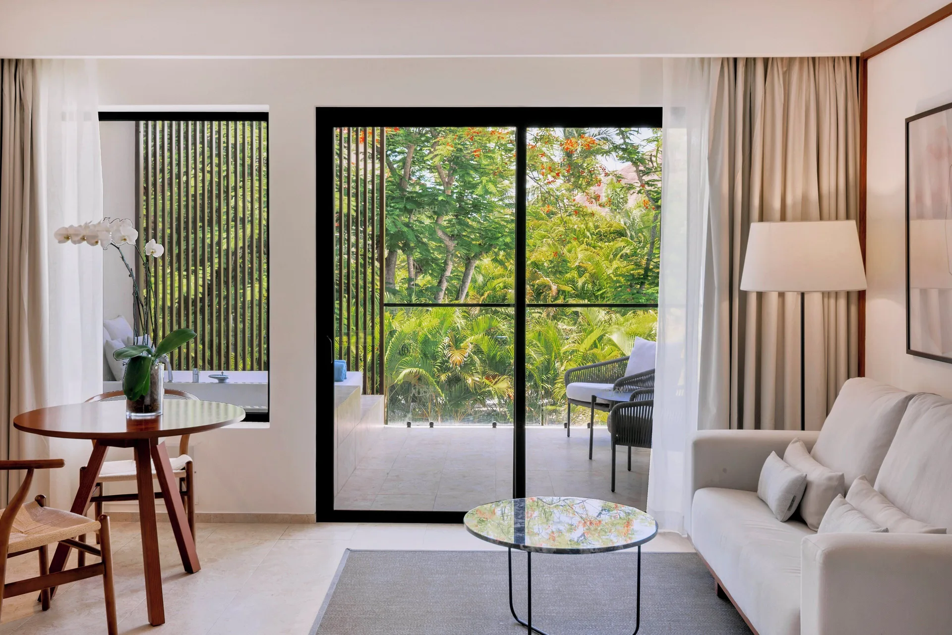 Sitting area and garden-facing balcony in a Junior Suite Deluxe Garden View at Live Aqua Punta Cana.