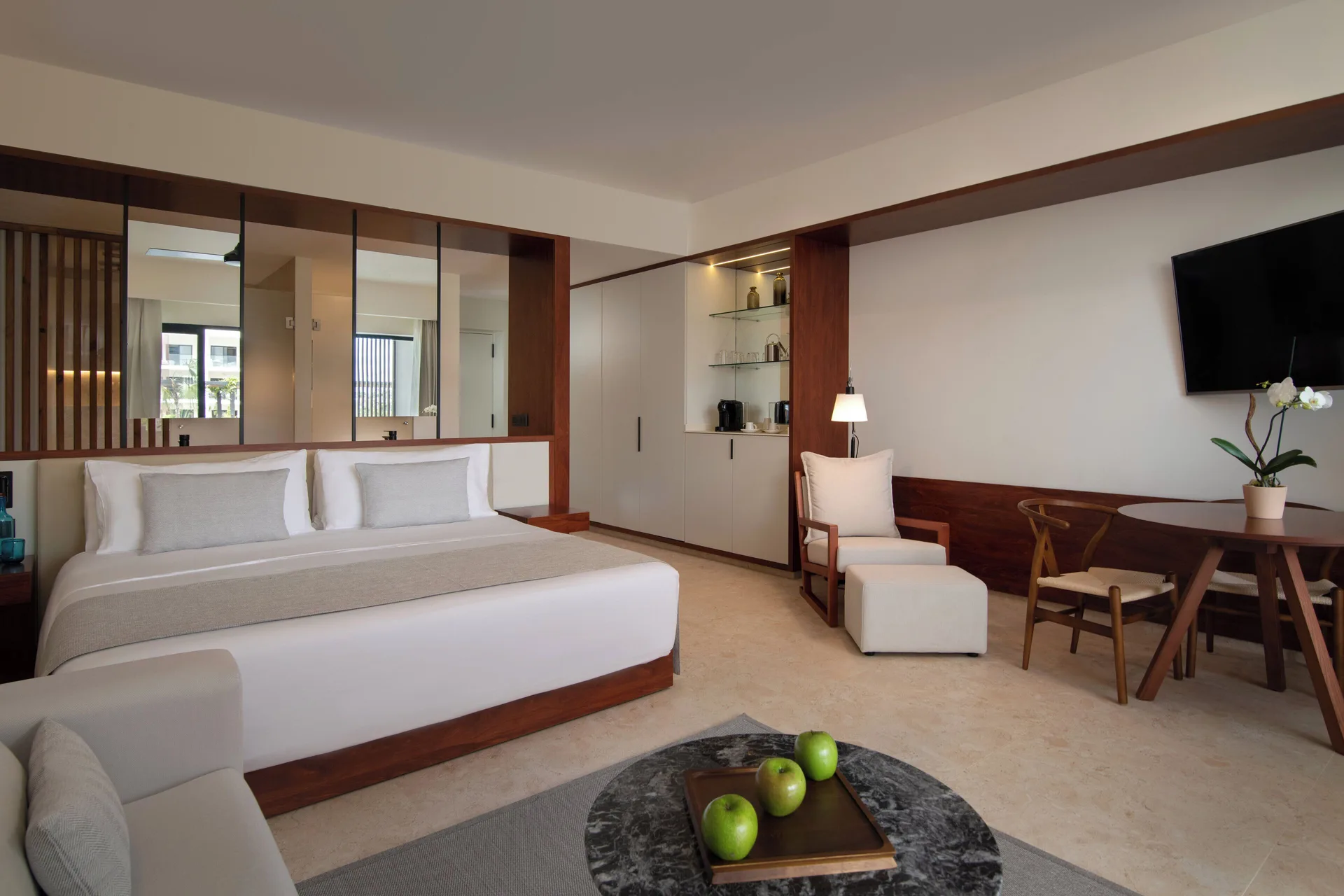 Junior Suite Deluxe Pool View with king bed, dining table and TV at Live Aqua Punta Cana.
