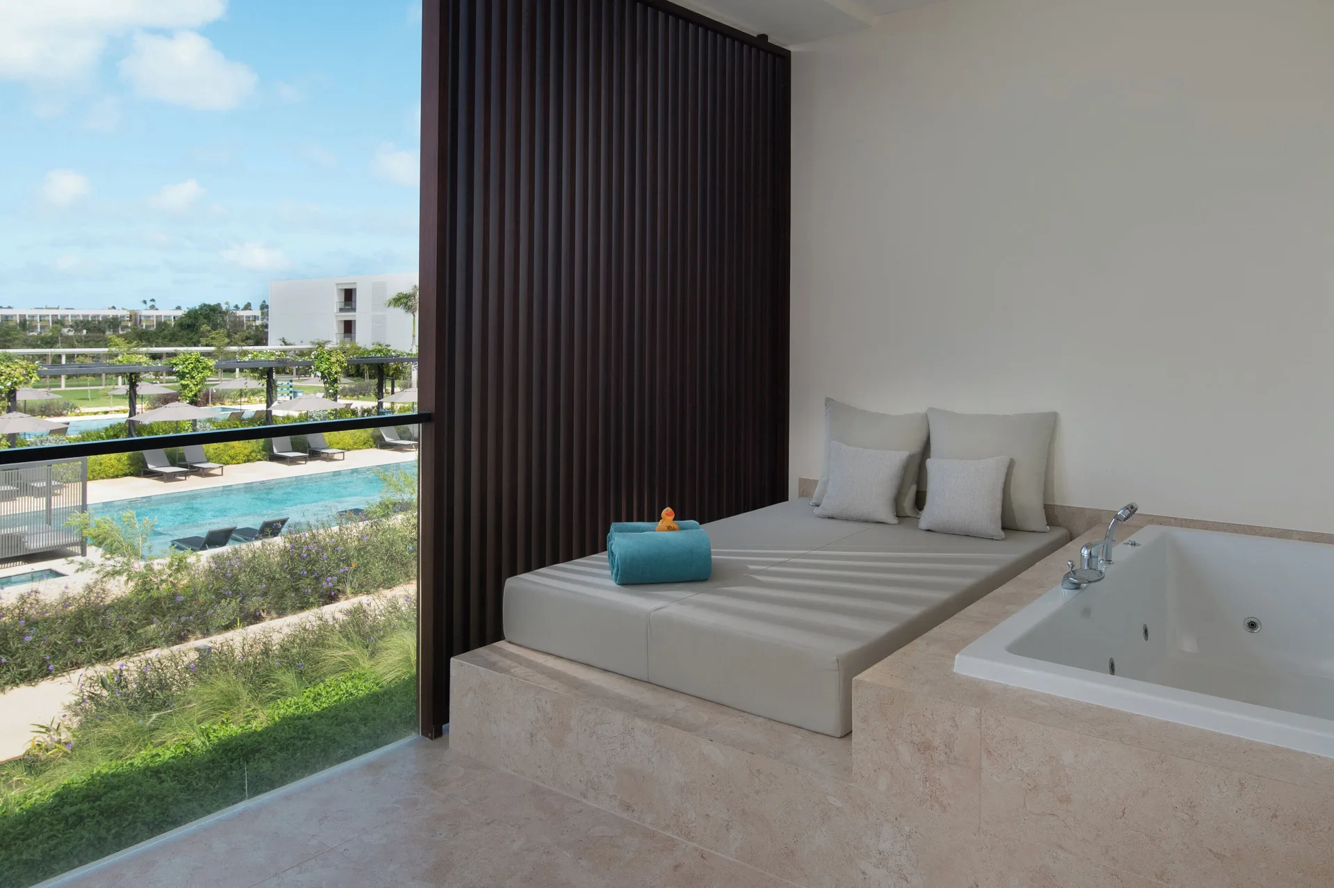 Junior Suite Deluxe Pool View terrace daybed and whirlpool tub at Live Aqua Punta Cana.