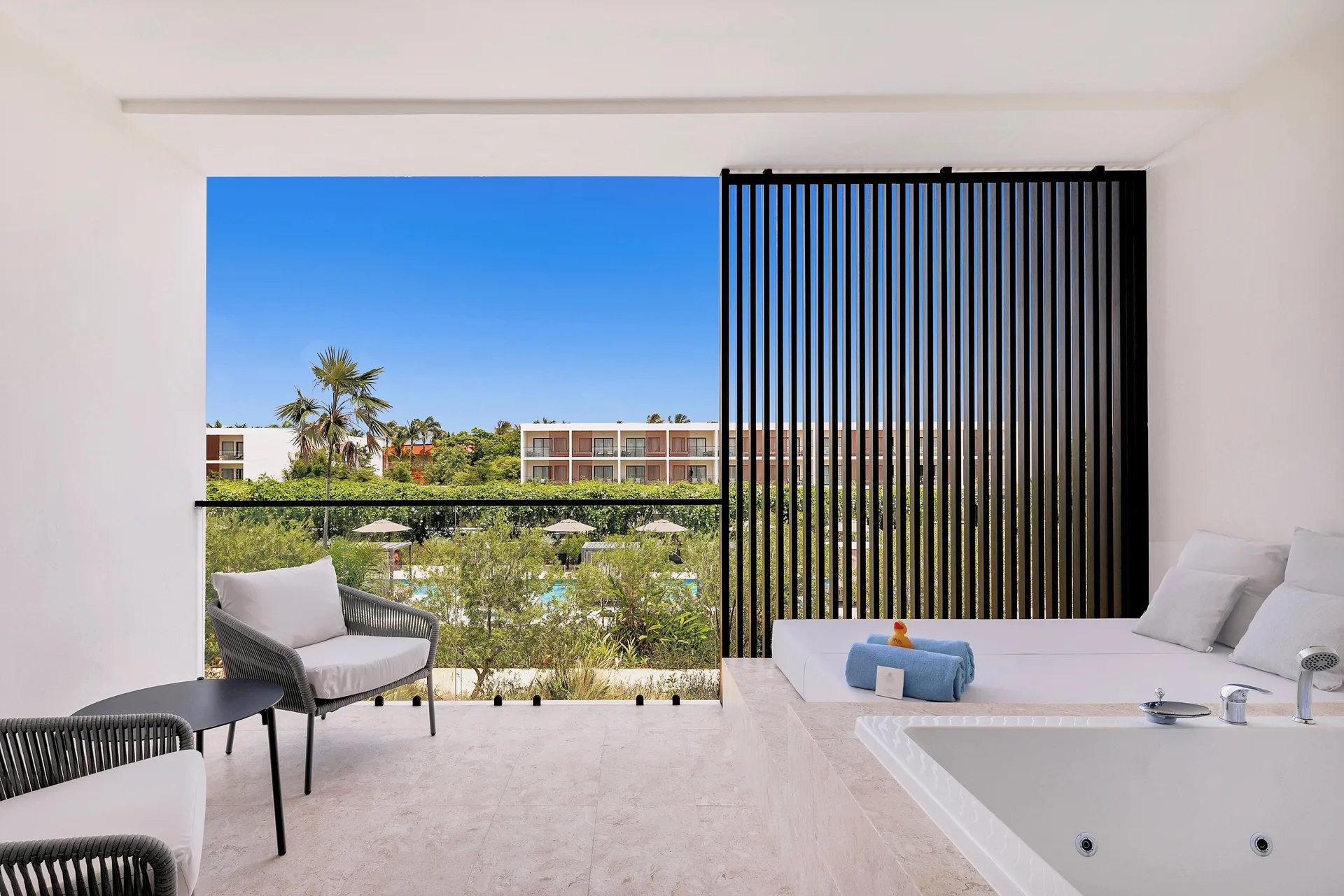 Pool-view terrace with whirlpool tub, daybed and chairs at Live Aqua Punta Cana.