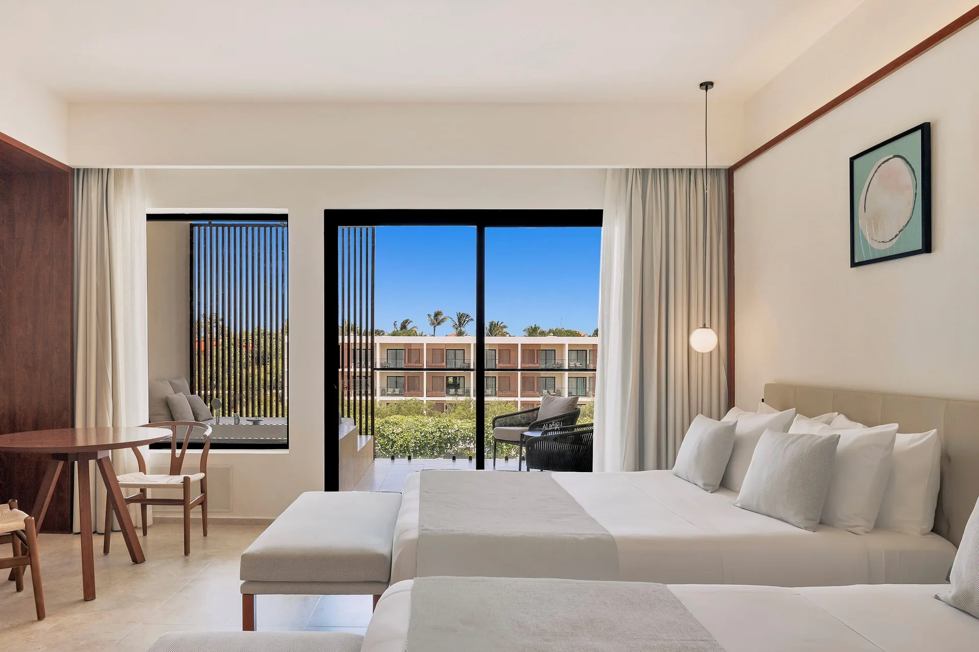 Two beds and balcony view in a Junior Suite Deluxe Pool View at Live Aqua Punta Cana.
