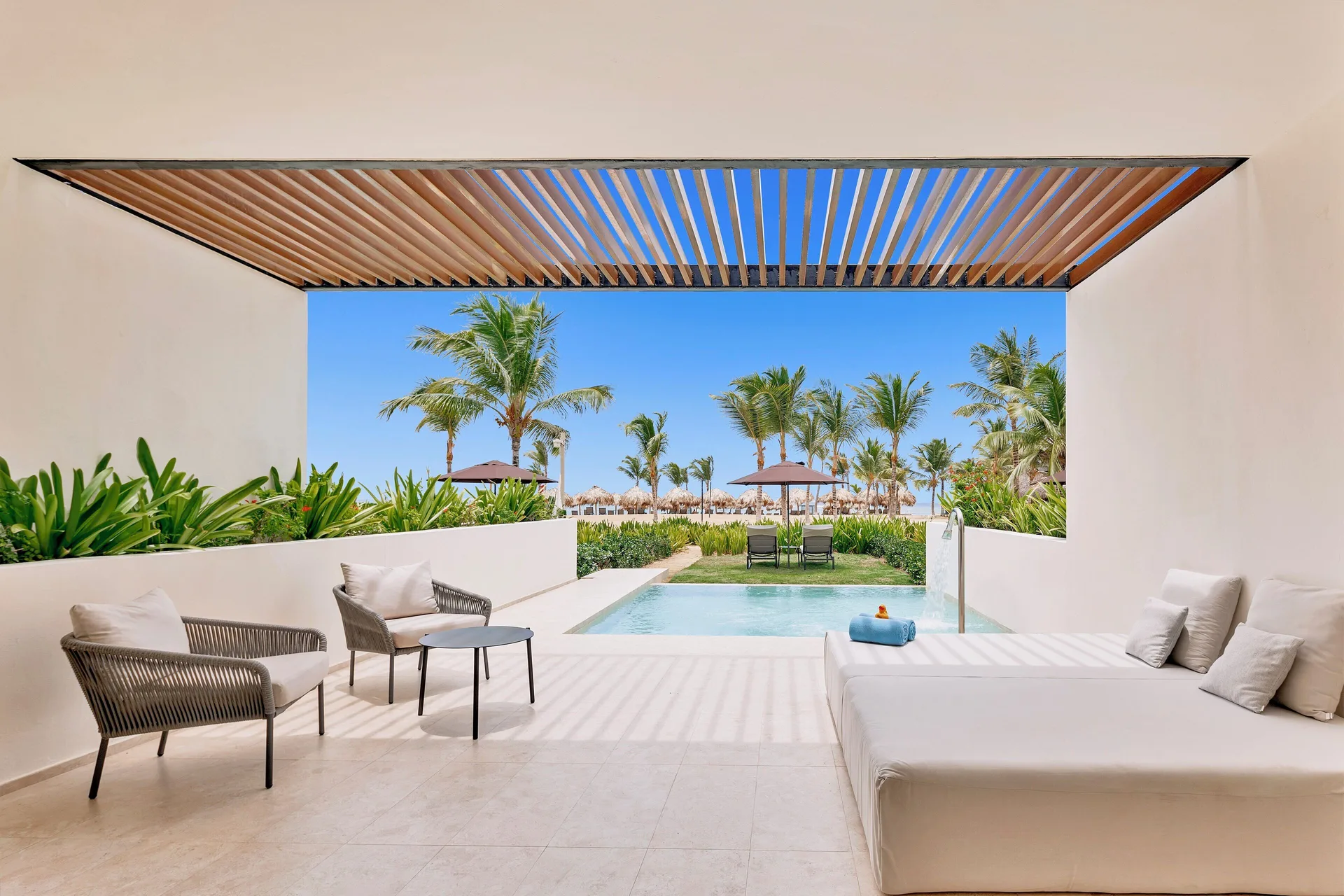 Tierra Suite Ocean Front covered terrace with seating, daybed, plunge pool, and palms at Live Aqua Punta Cana.