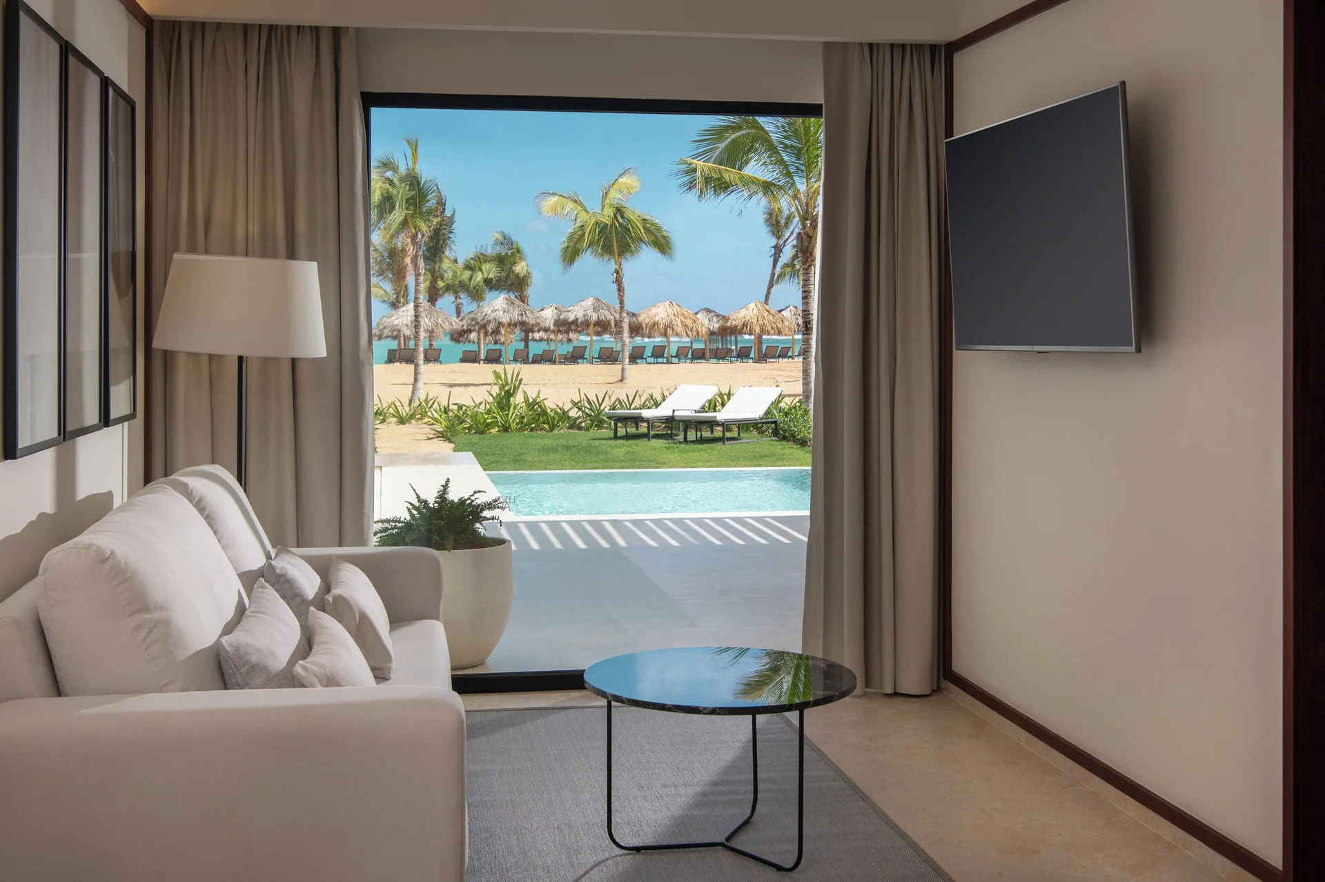 Tierra Suite Ocean Front living area with sofa, TV, and beach view at Live Aqua Punta Cana.
