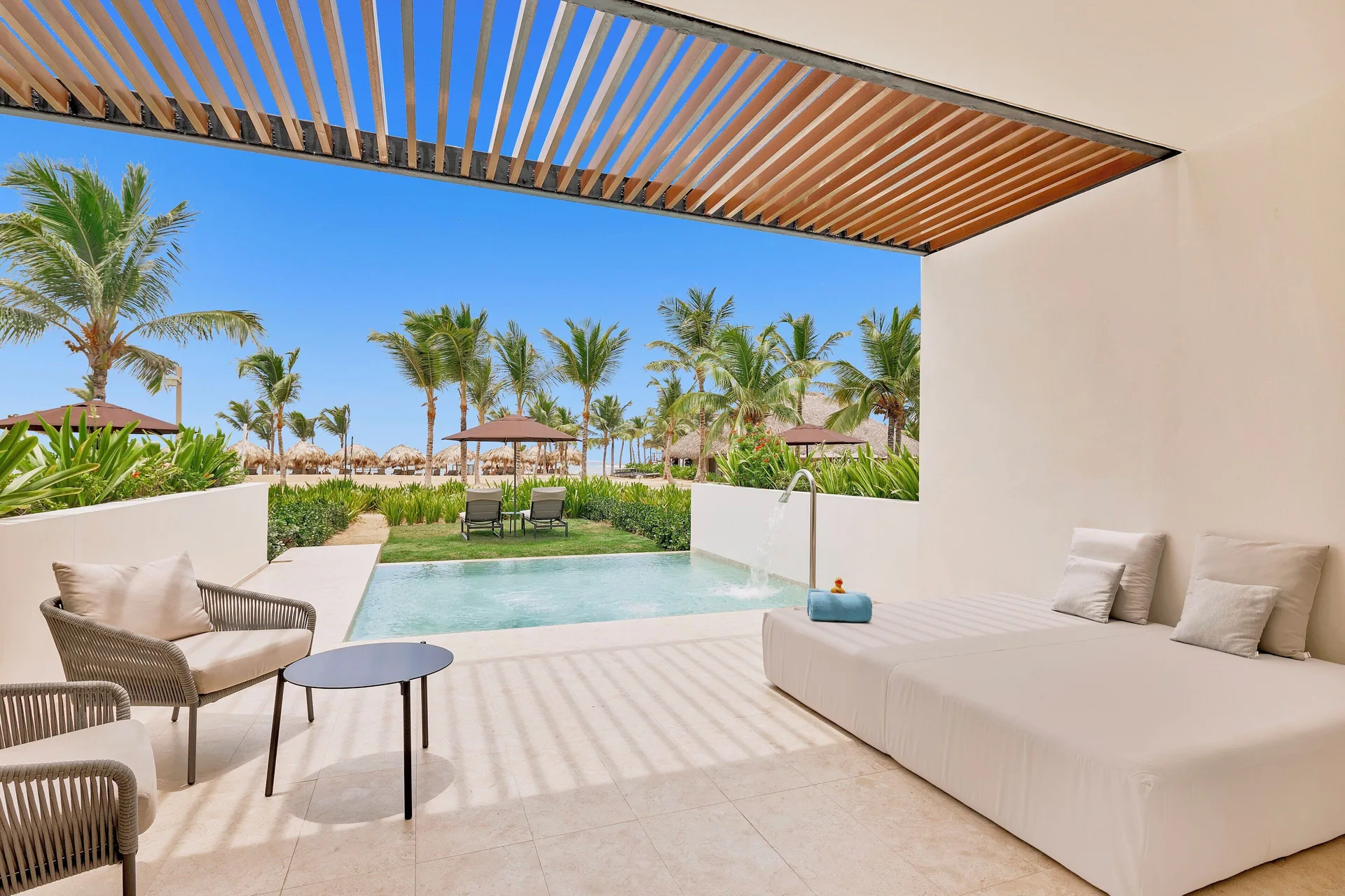Tierra Suite Ocean Front patio with daybed, chairs, plunge pool, and palms at Live Aqua Punta Cana.