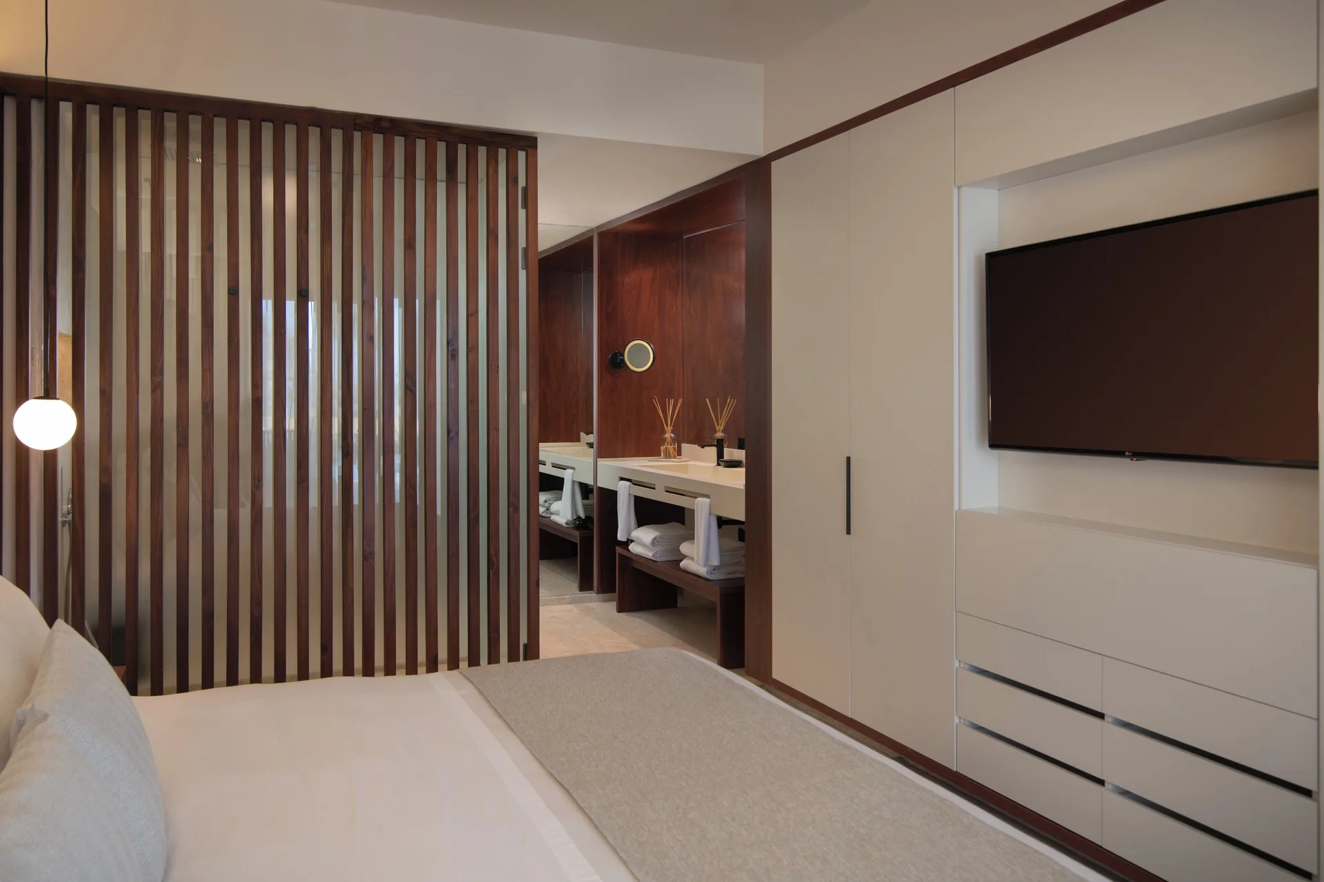 Viento Suite Ocean Front king bed, TV wall, and vanity at Live Aqua Punta Cana.