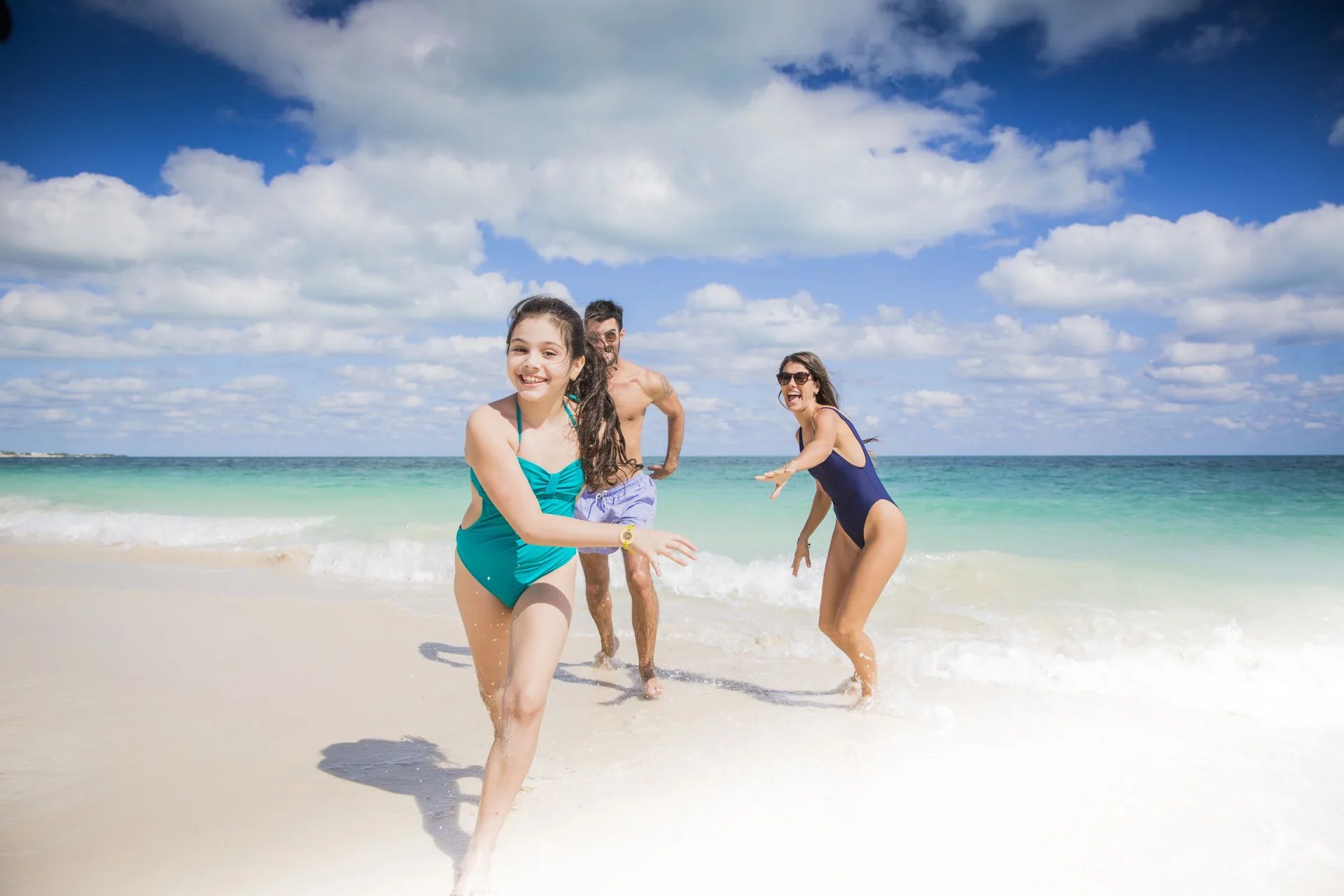Family playing in the surf on the beach at Majestic Elegance Costa Mujeres.