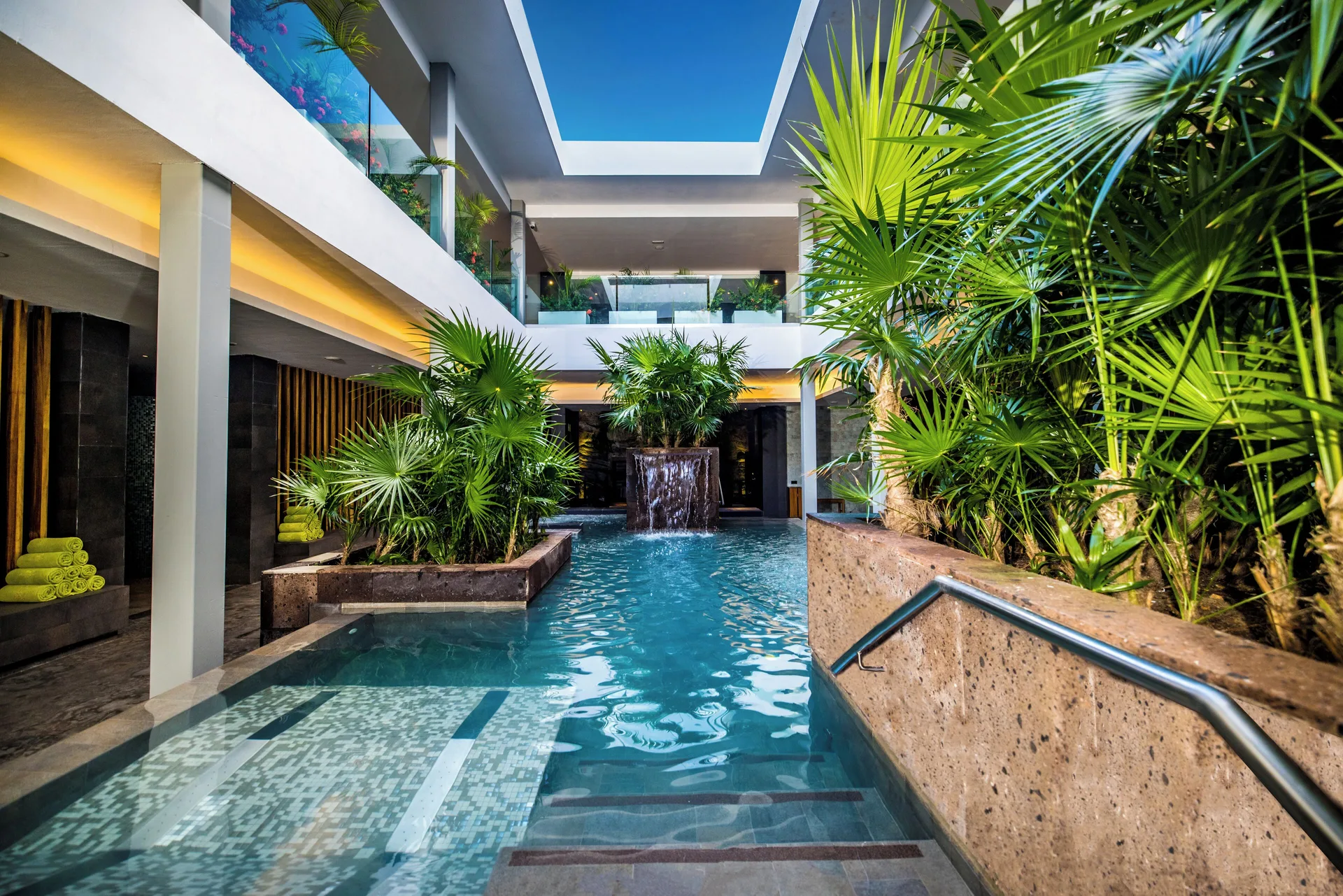 Indoor spa pool with tropical plants and a waterfall at Majestic Elegance Costa Mujeres.