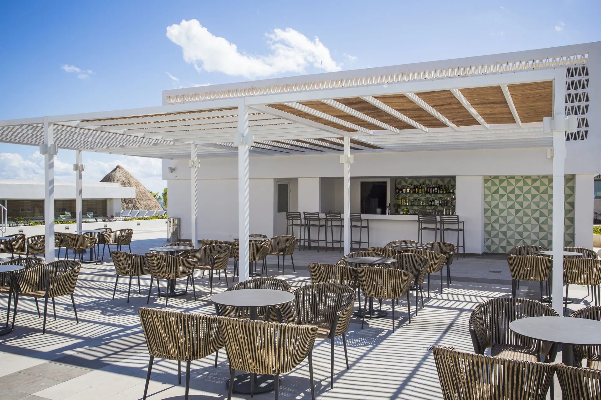 Open-air terrace bar with woven chairs at Majestic Elegance Costa Mujeres.