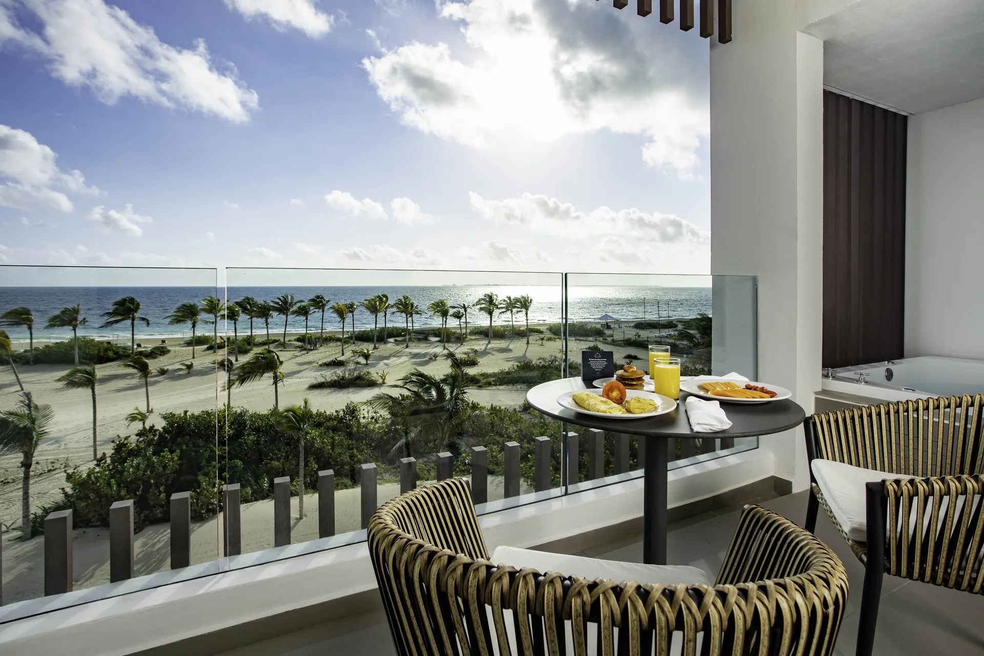 Balcony dining setup and outdoor Jacuzzi with ocean view at Majestic Elegance Costa Mujeres.