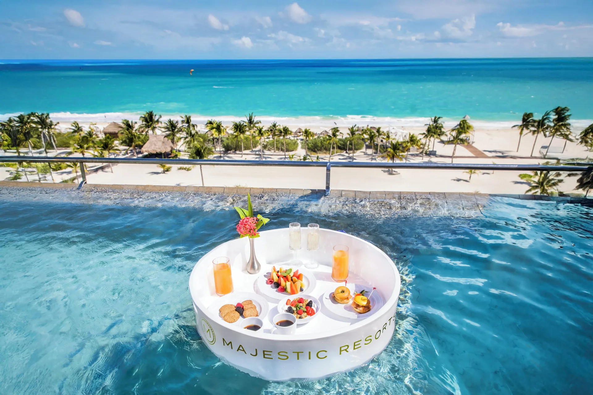 Floating breakfast in an oceanfront plunge pool at Majestic Elegance Costa Mujeres above the beach.
