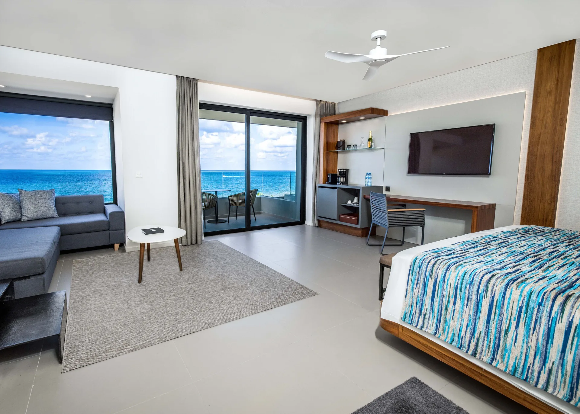 Oceanfront suite bedroom at Majestic Elegance Costa Mujeres with king bed, sofa, balcony, and sea view.