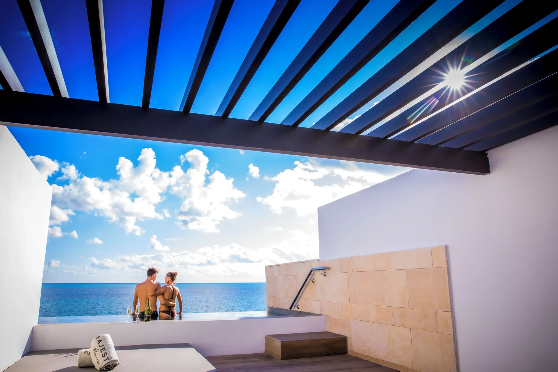 Private oceanfront terrace at Majestic Elegance Costa Mujeres with plunge pool, pergola, and guests.